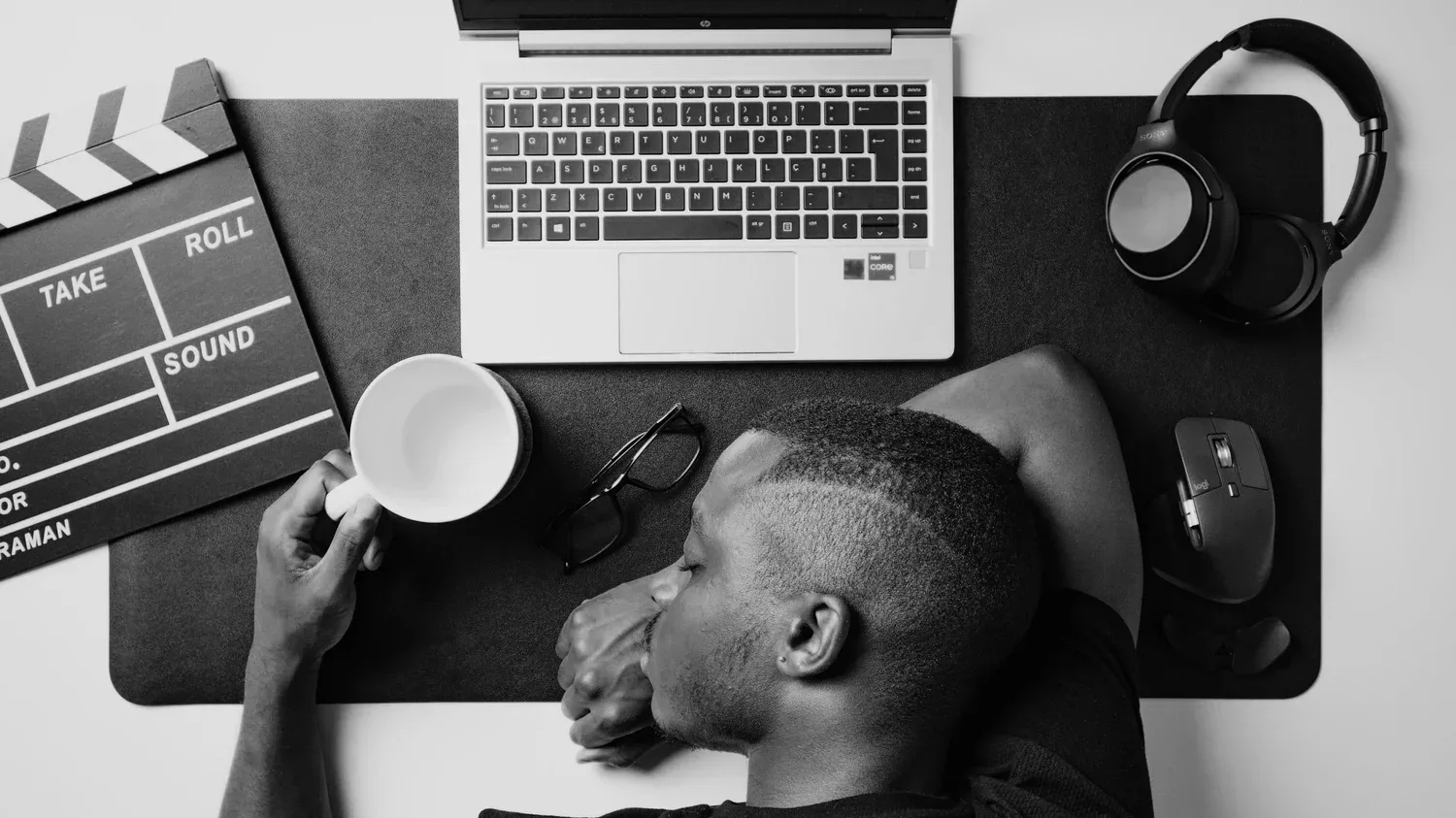 Overhead view of a person working at a desk with a laptop, headphones, and clapperboard