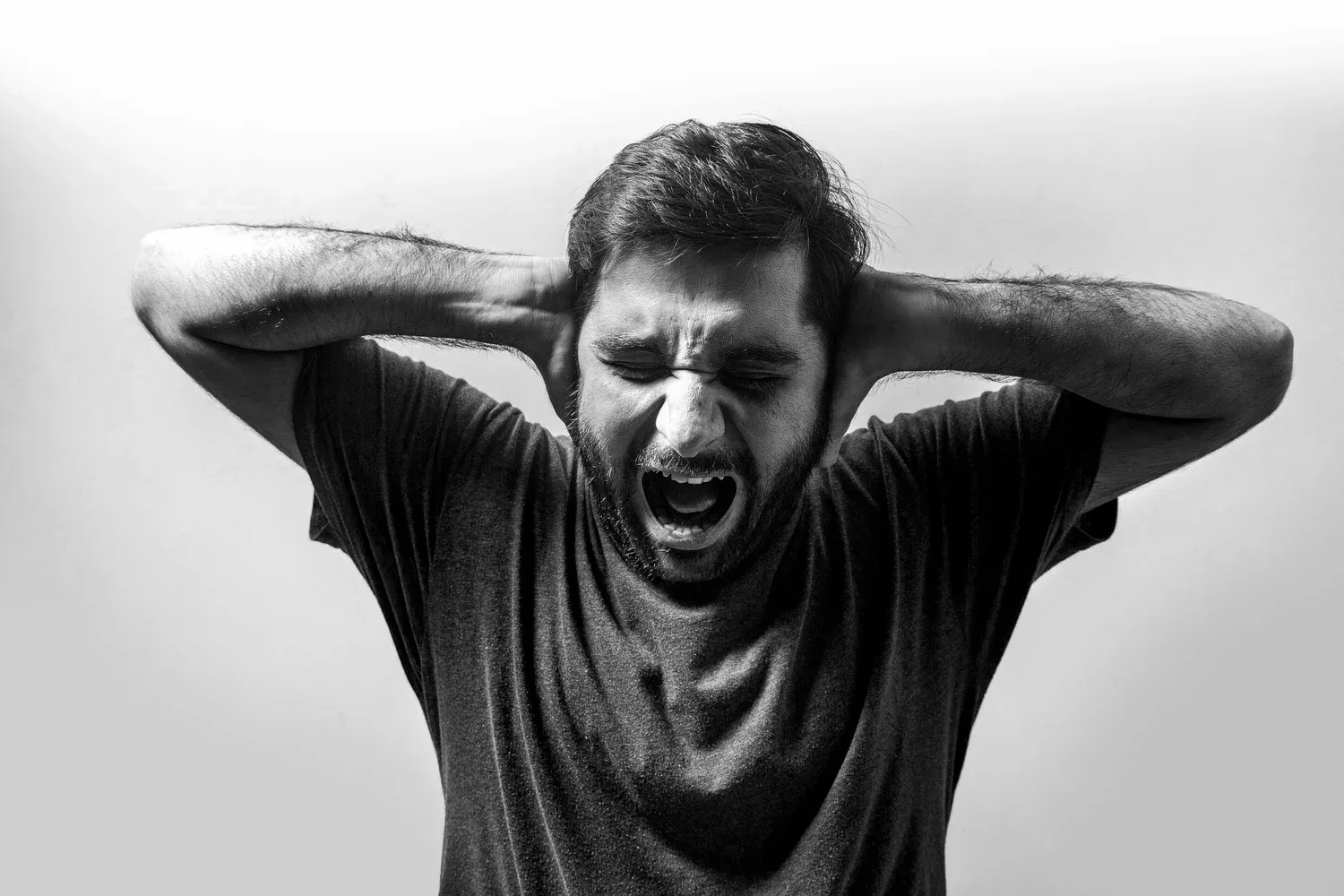 Black-and-white photo of a man covering his ears and shouting