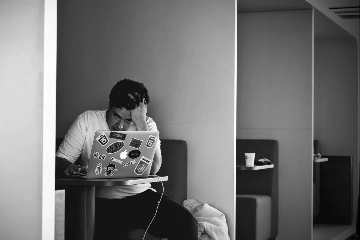 Black-and-white photo of a man sitting at a desk looking at a laptop