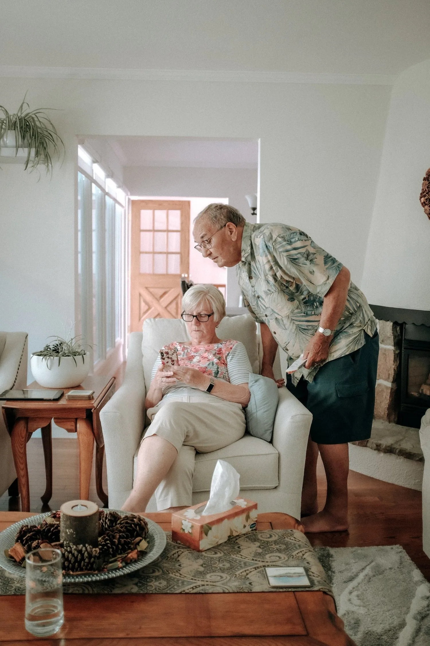 Older couple relaxing together in a sunny, plant-filled living room