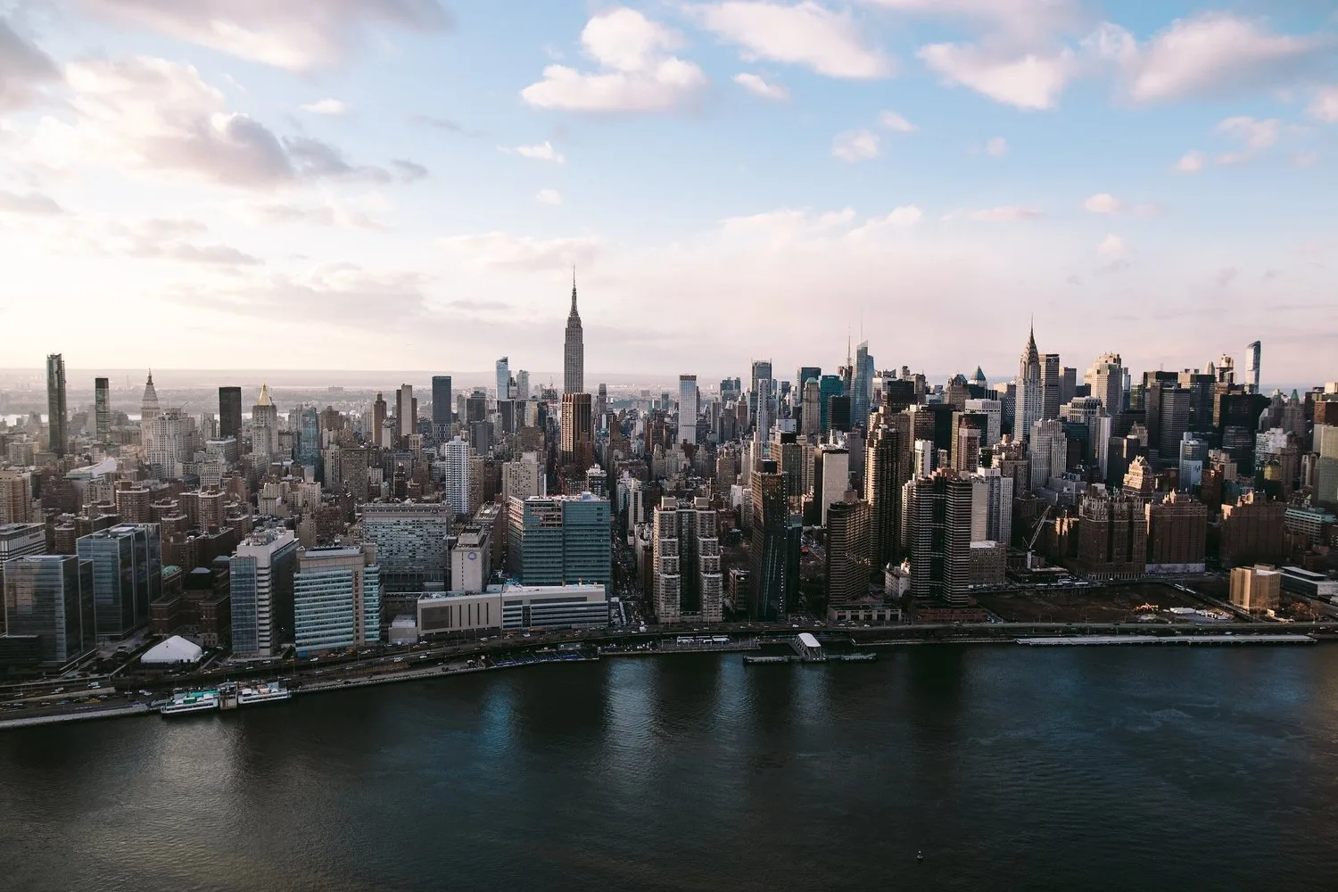 New York City skyline across the water under a partly cloudy sky