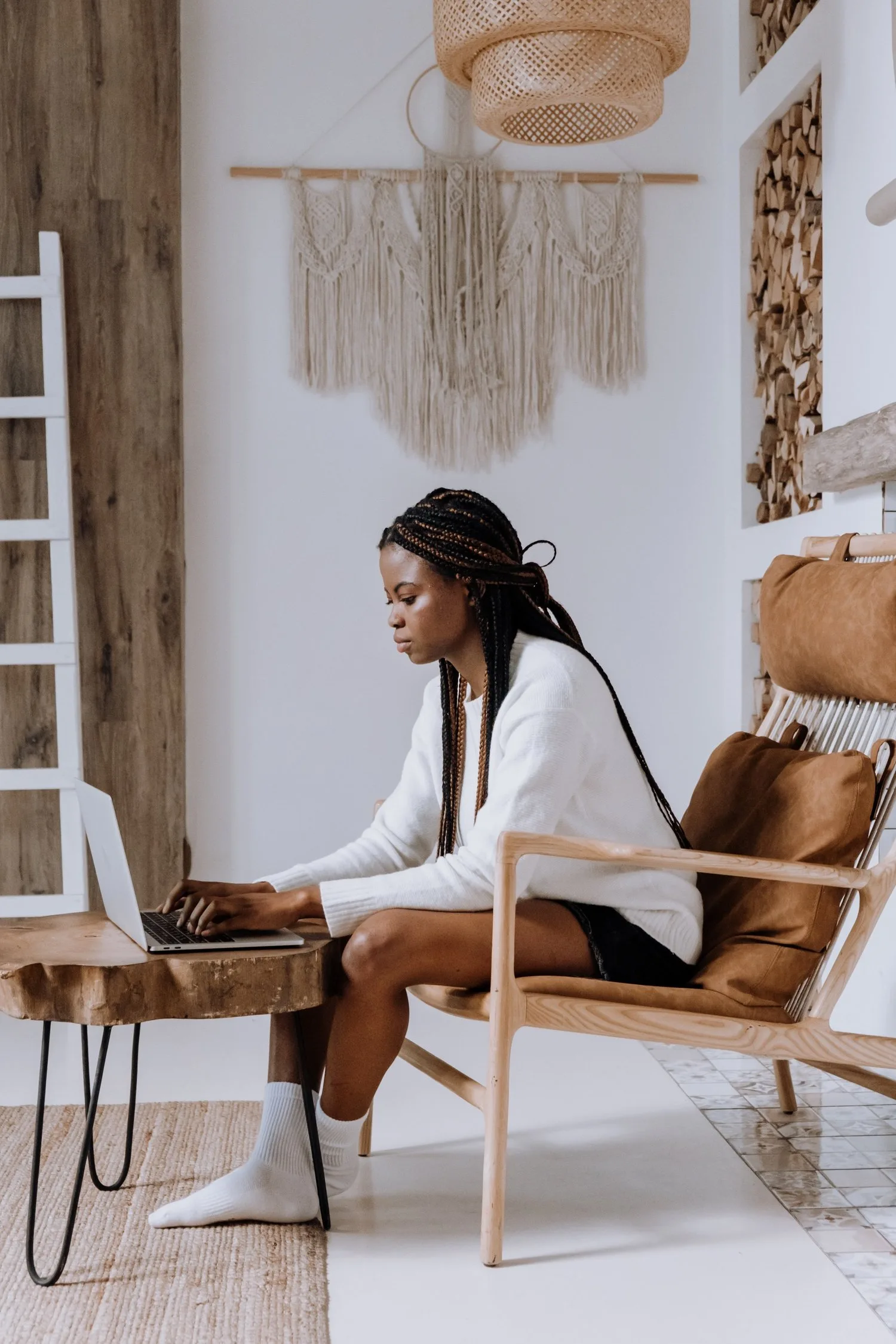 Woman seated at a small desk in a bright, bohemian-style room