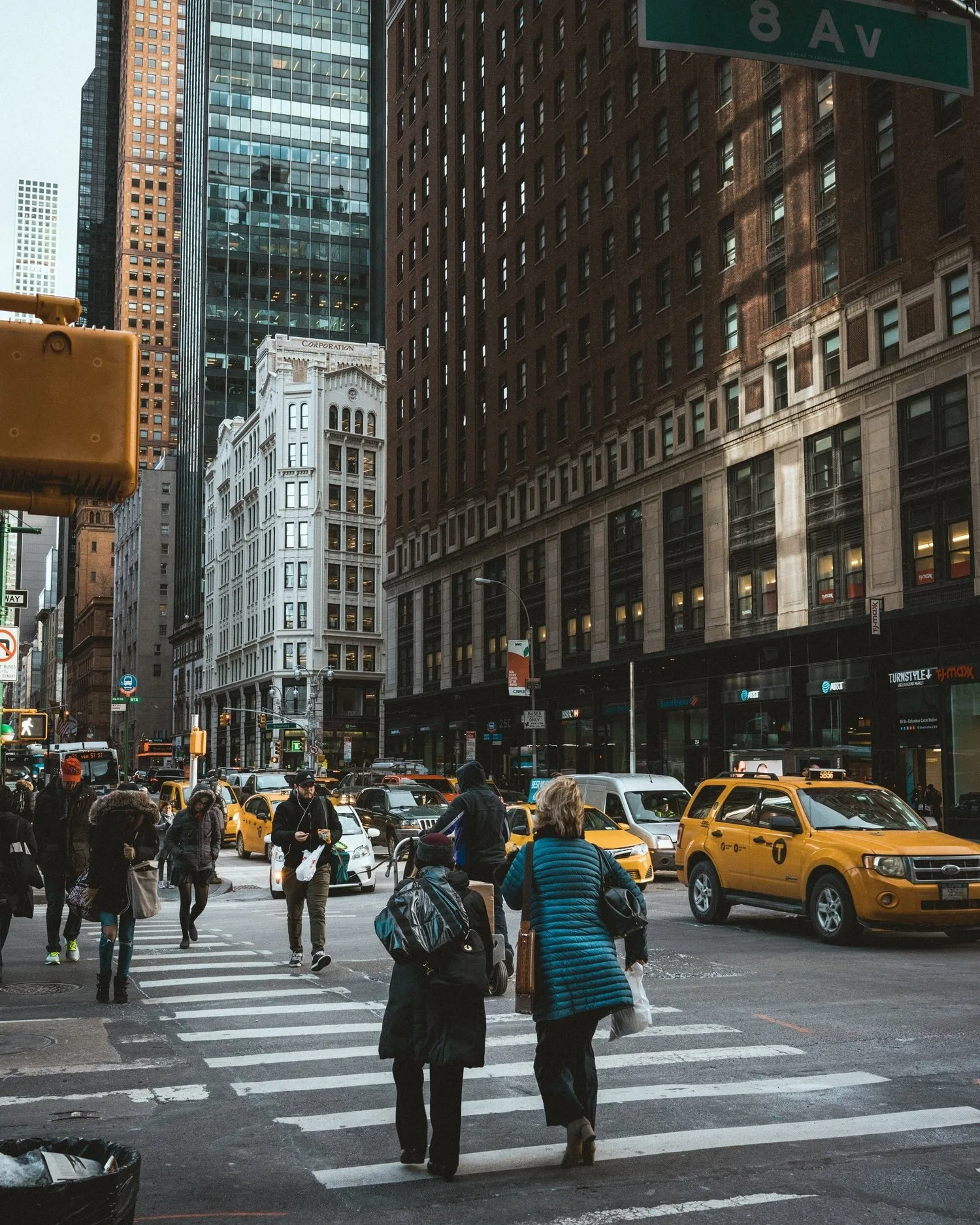 Pedestrians crossing a busy Manhattan street lined with tall buildings