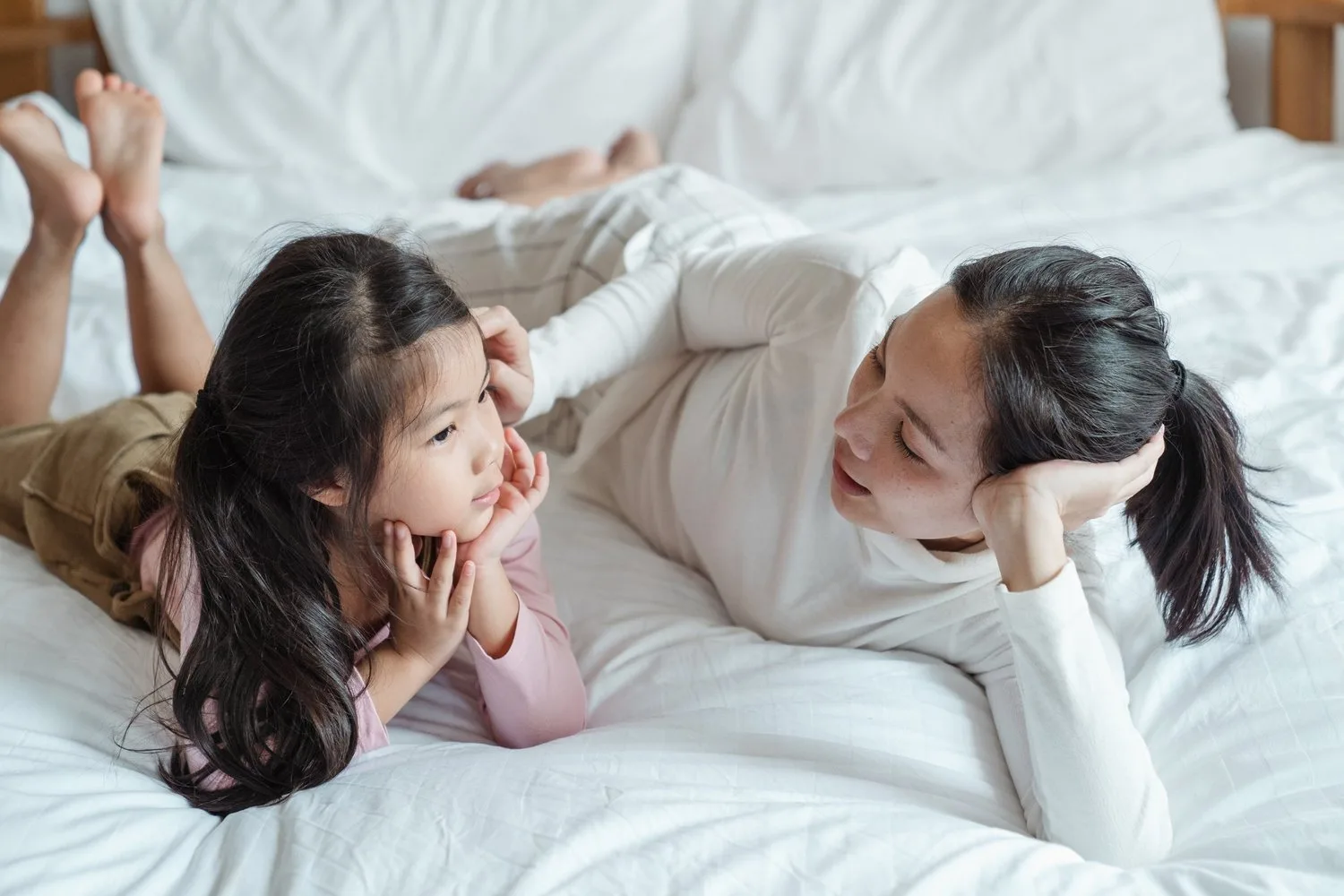 Two young girls lying on a bed laughing together