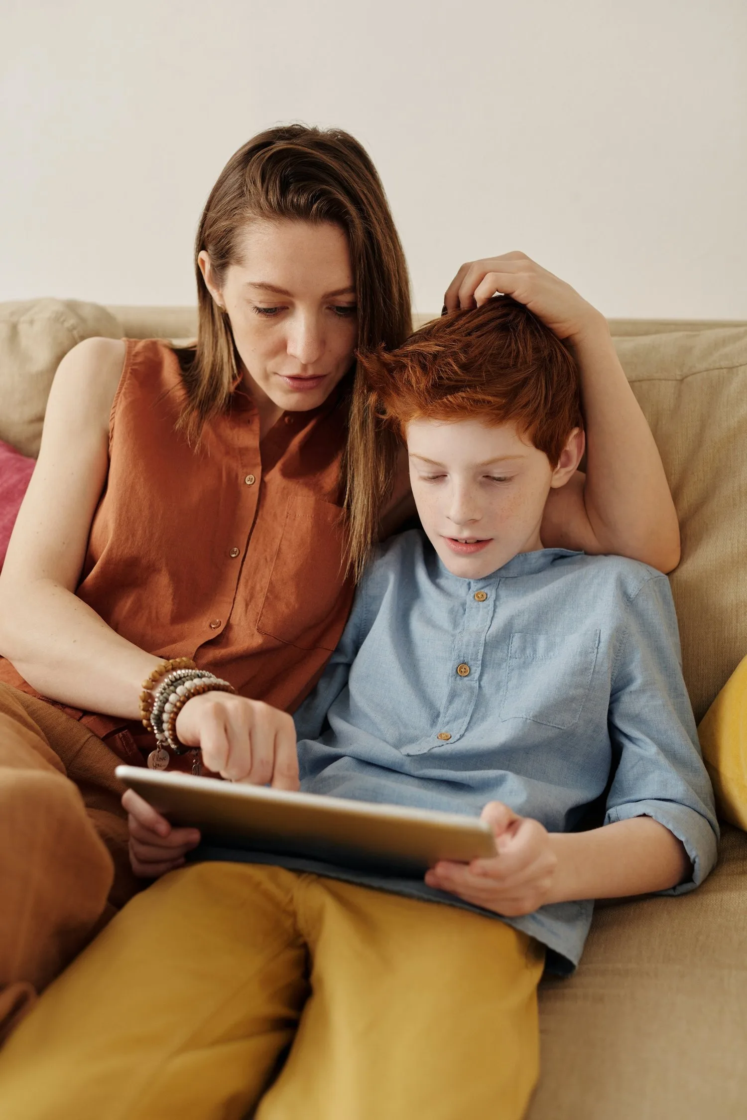 Mother and son looking at a tablet together on a sofa