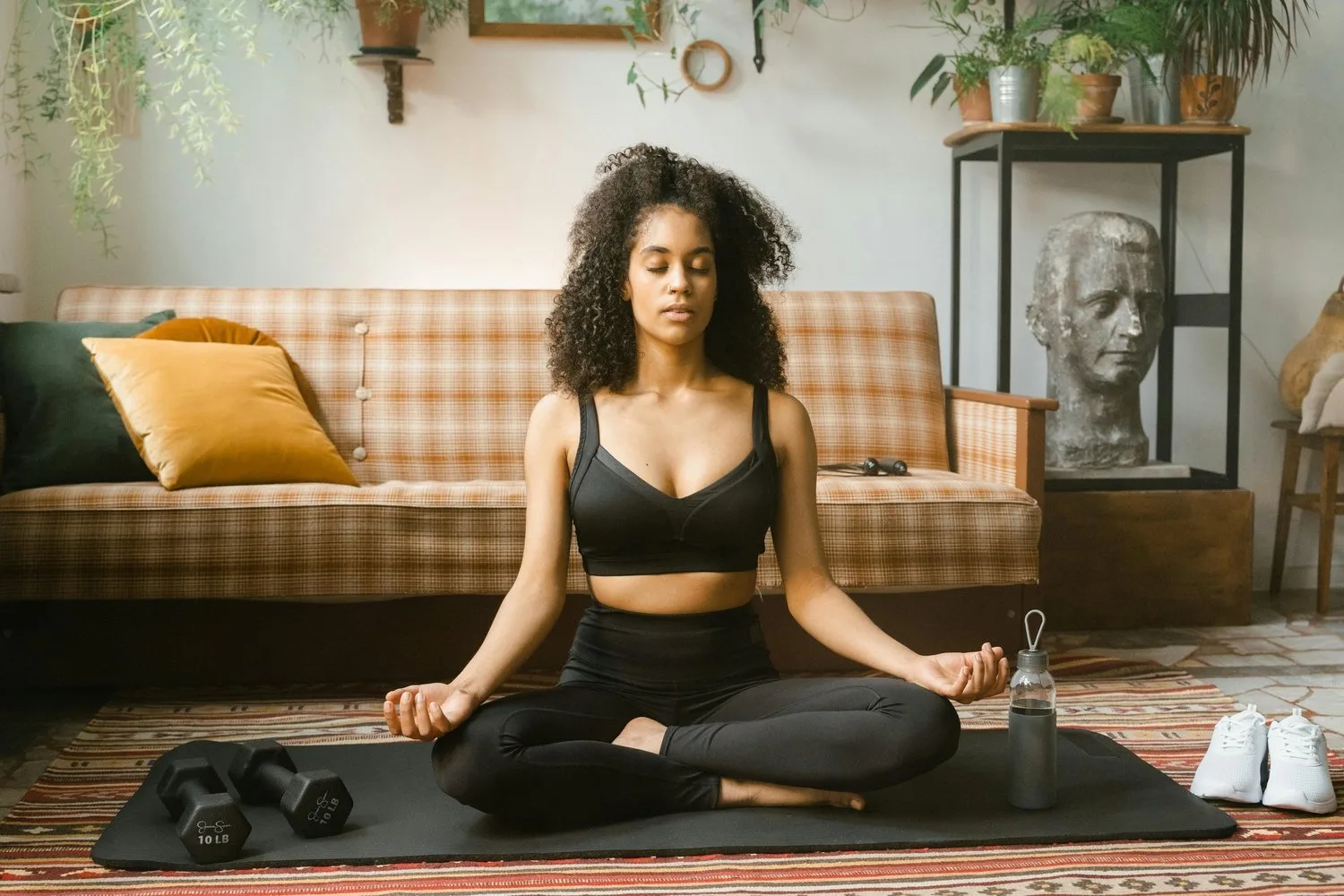 Woman meditating cross-legged on a mat in a cozy living room