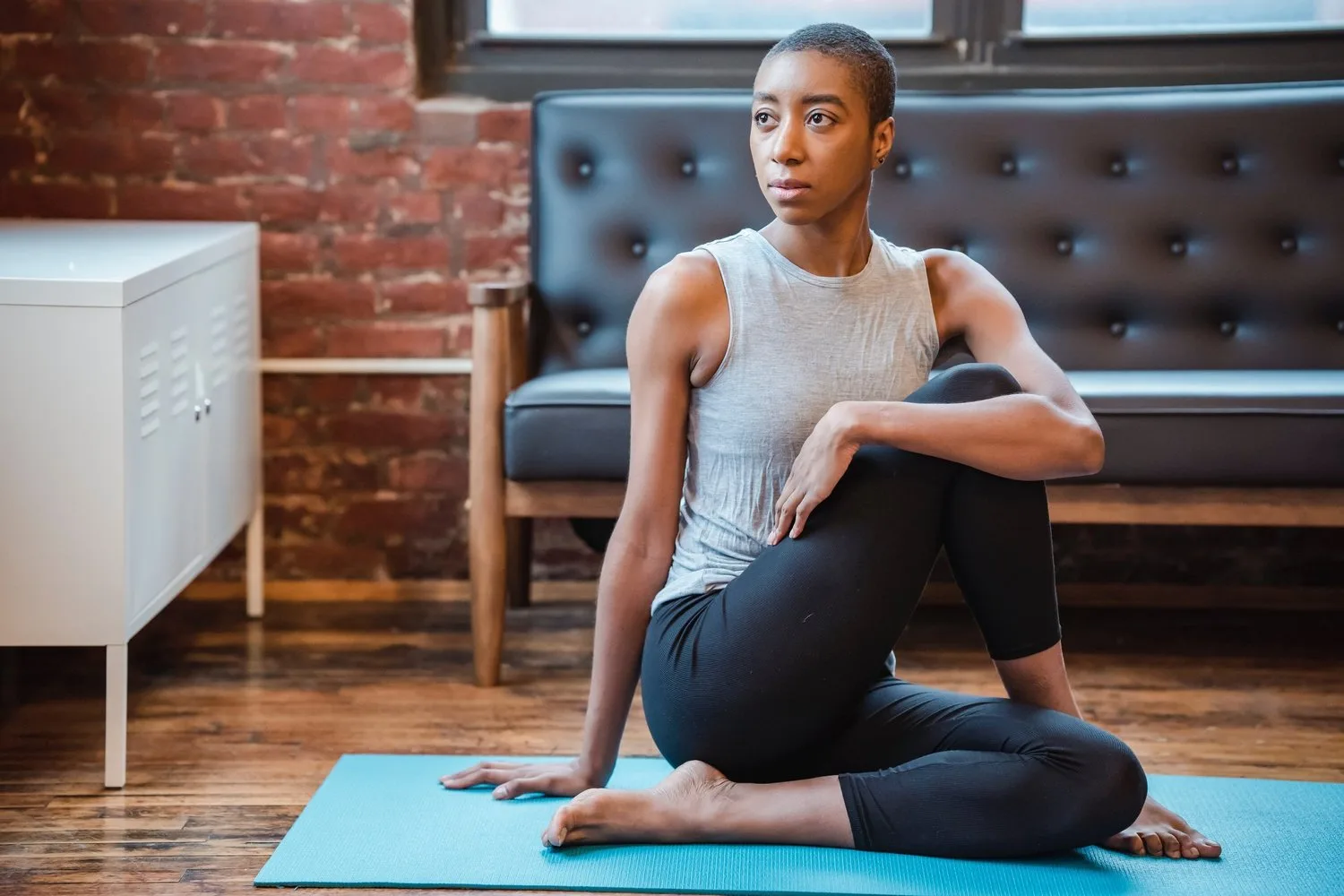 Woman seated on a yoga mat in a twisting stretch in a living room