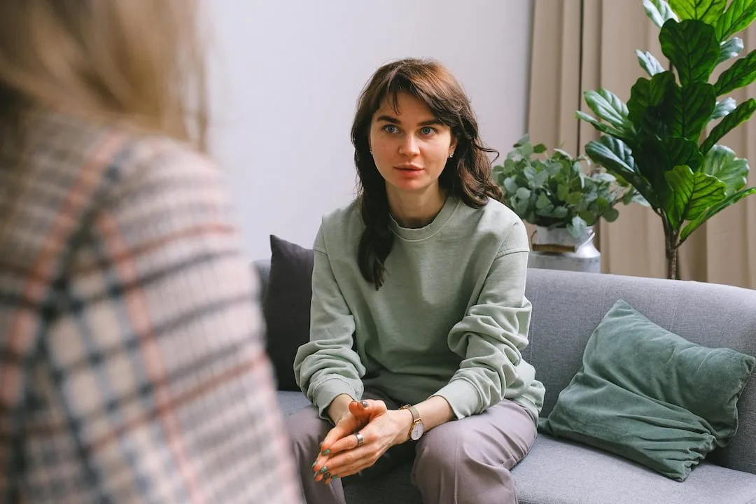 Woman sitting on a sofa listening to someone seated across from her