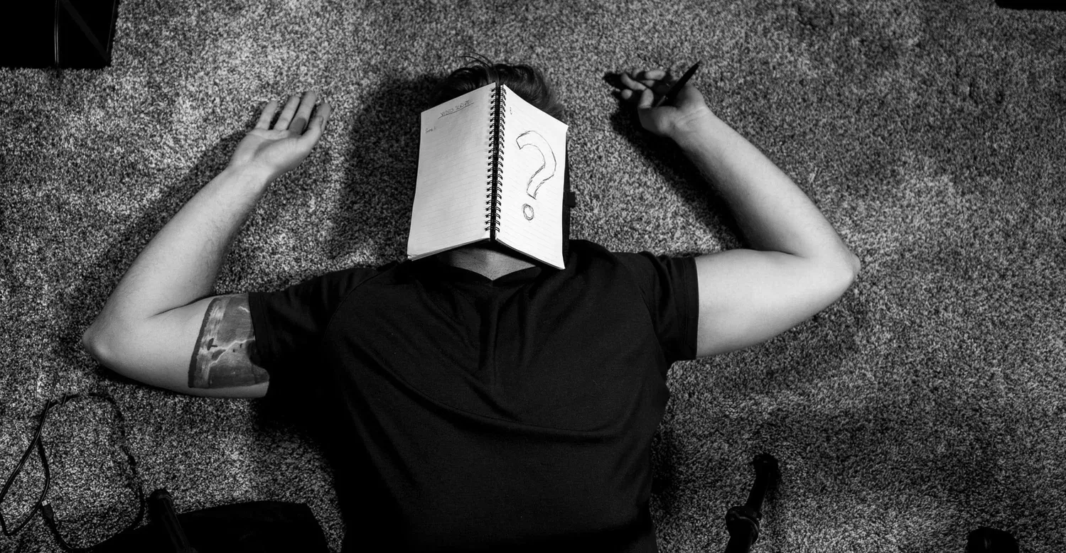 Person lying on the ground with an open book covering their face