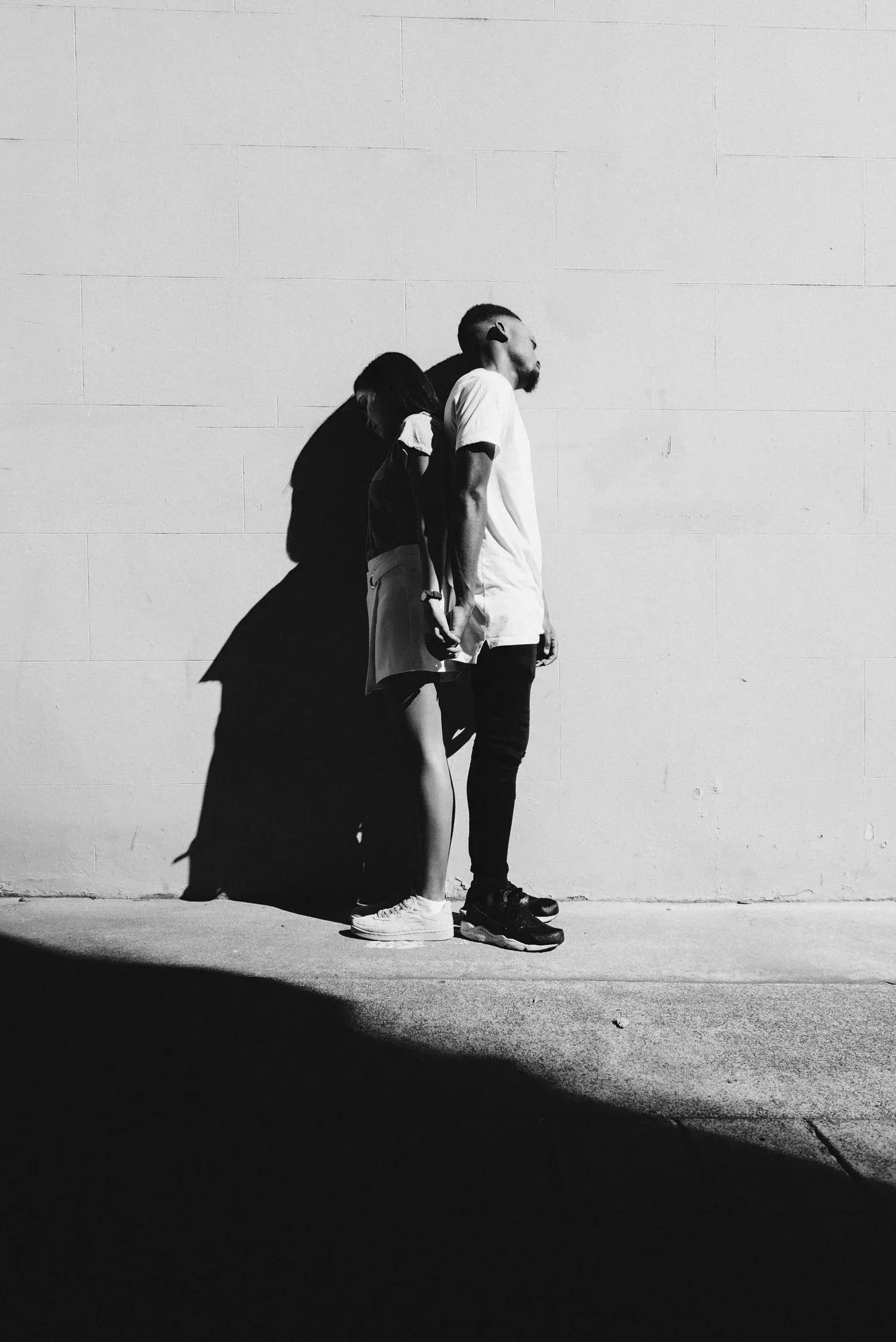 Black-and-white photo of a couple embracing against a bright wall