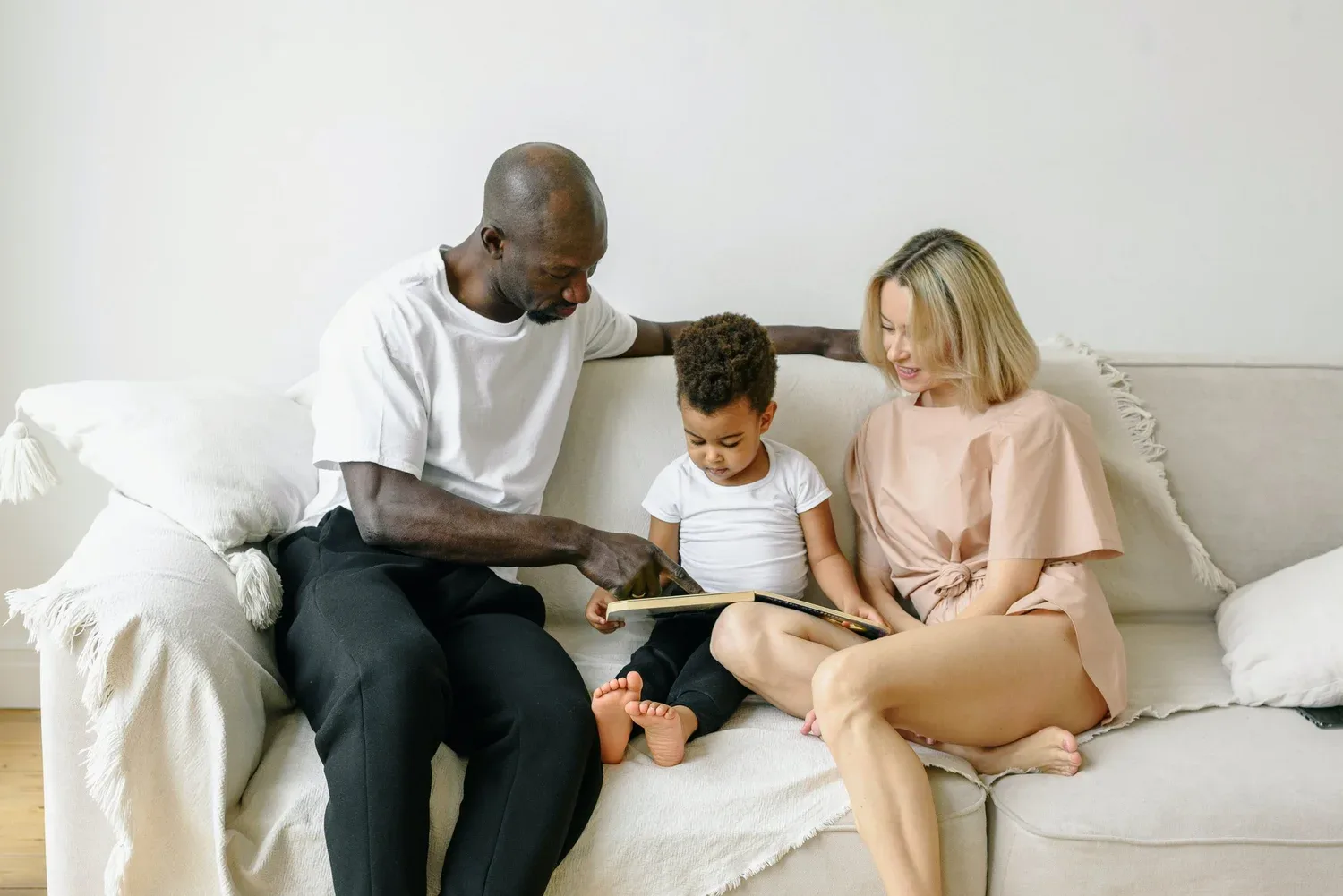Parents sitting on a sofa reading with their young son