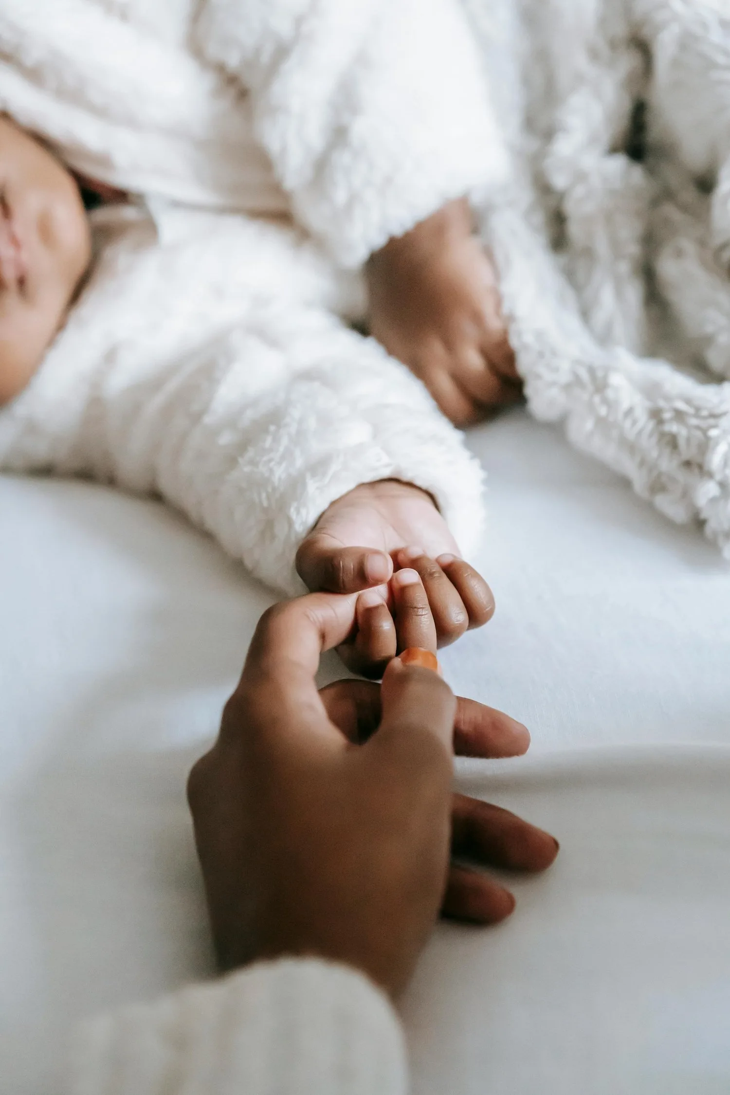 Adult hand holding a baby’s tiny hand