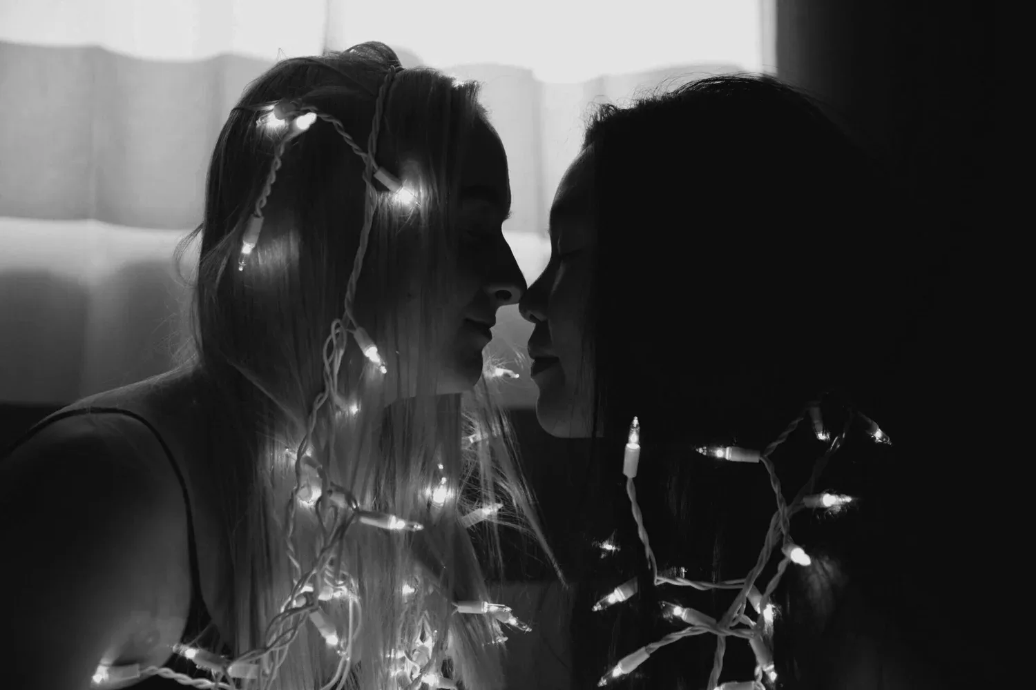 Black-and-white photo of two people facing each other beneath string lights