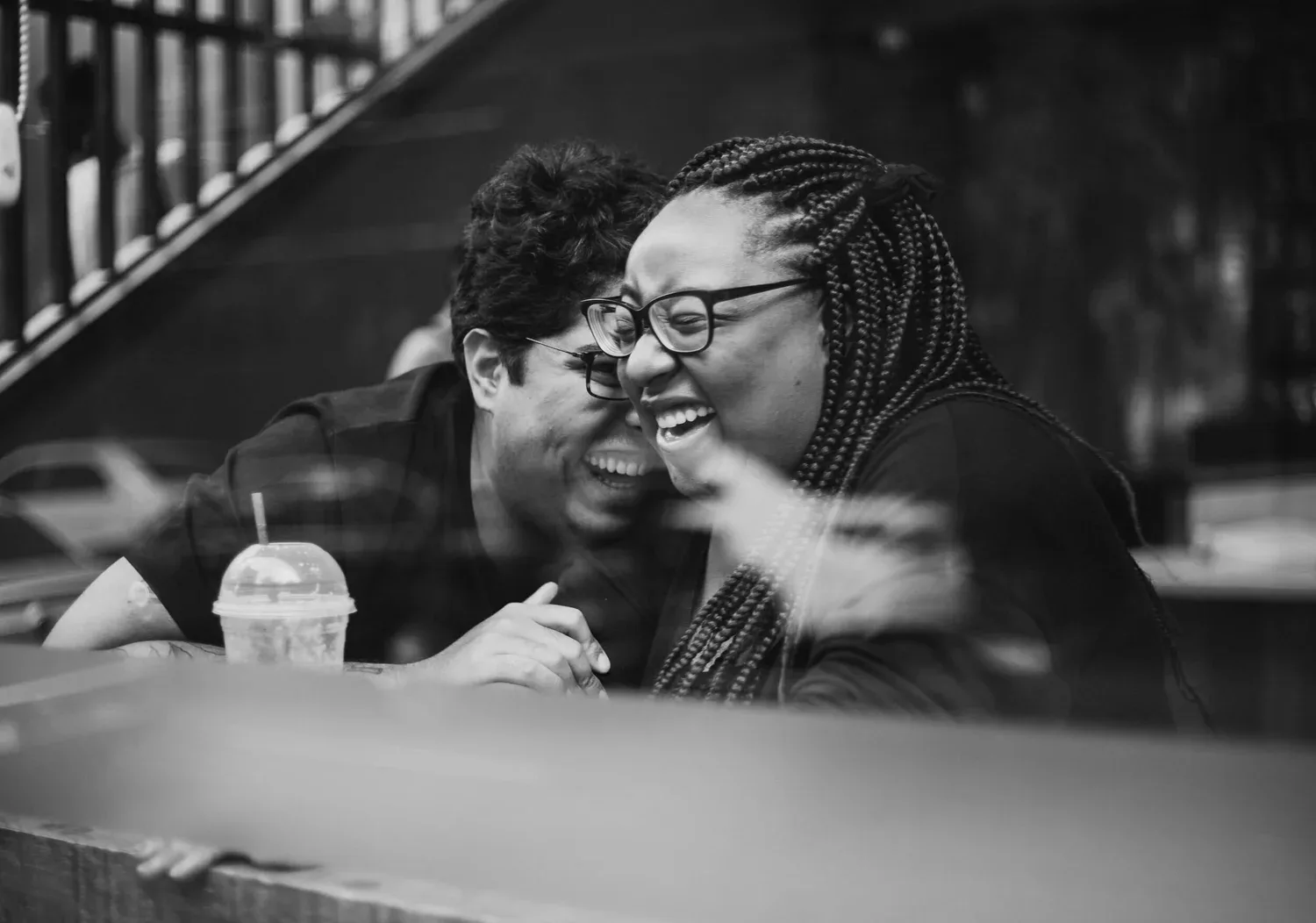 Black-and-white photo of two people laughing together at a table