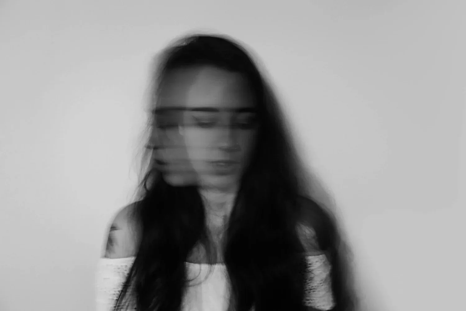 Black-and-white photo of a woman with long hair, face blurred in motion