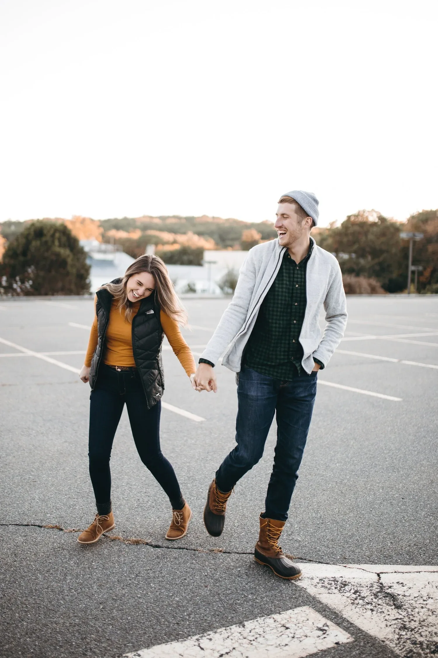 Couple walking hand in hand across an empty parking lot