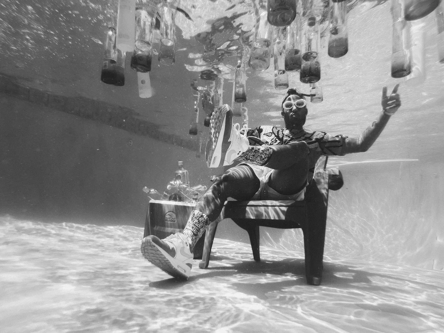 Black-and-white photo of a man in a suit seated on a chair underwater