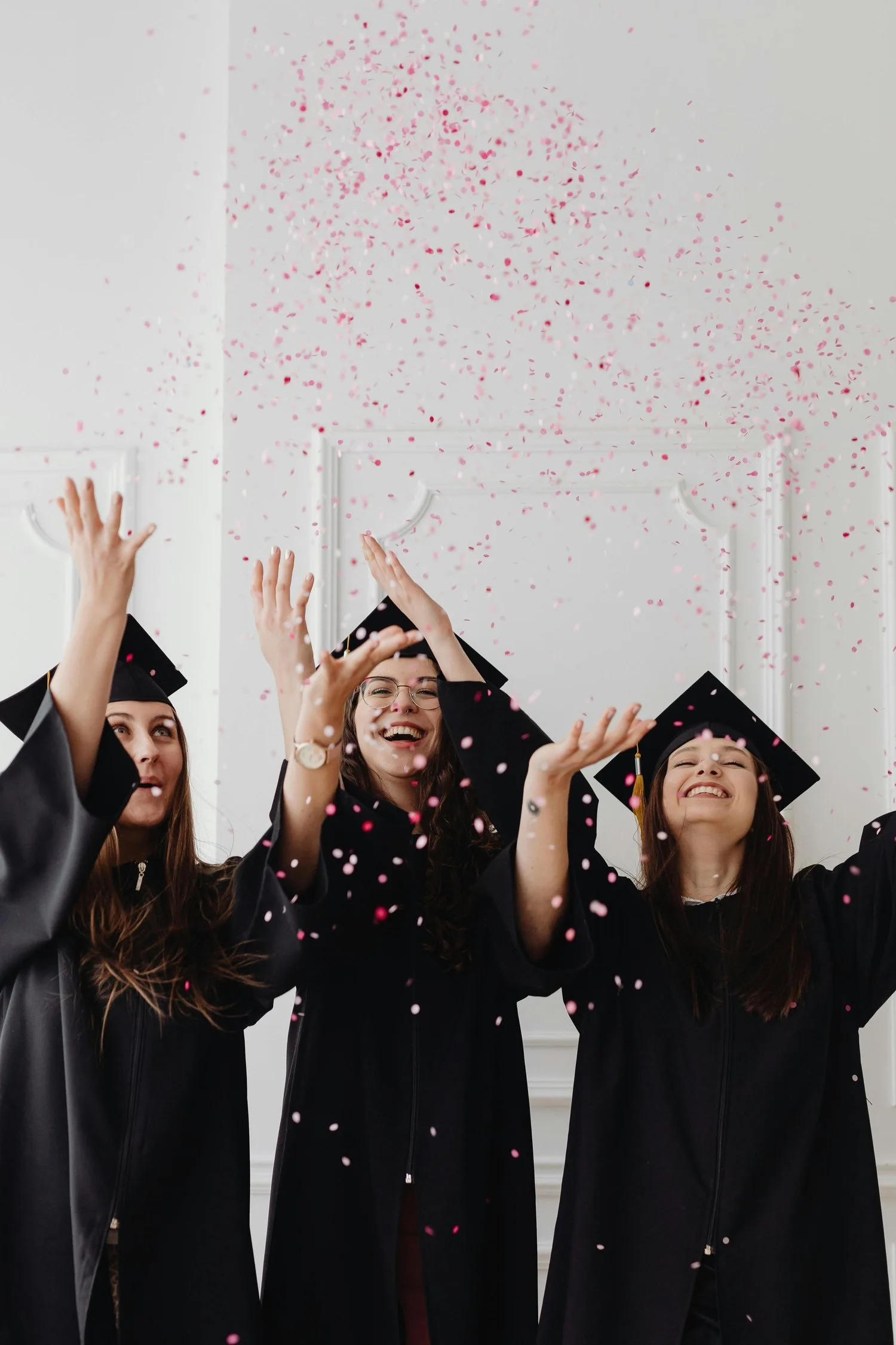 Graduates in caps and gowns celebrating as confetti falls