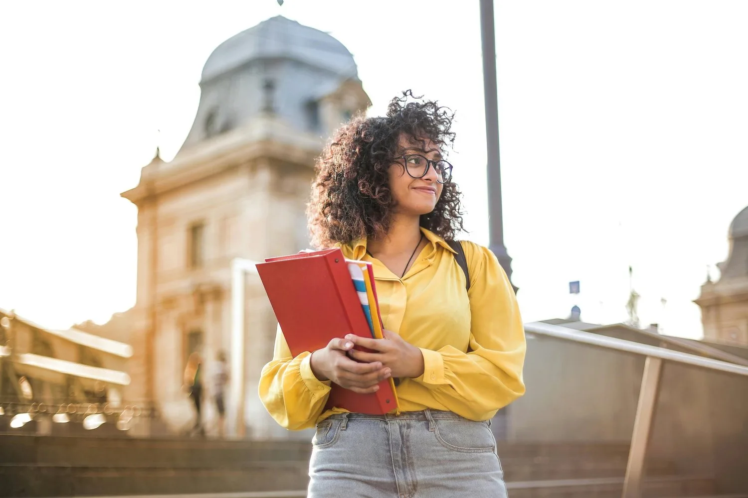Smiling college student holding a notebook on a sunny campus