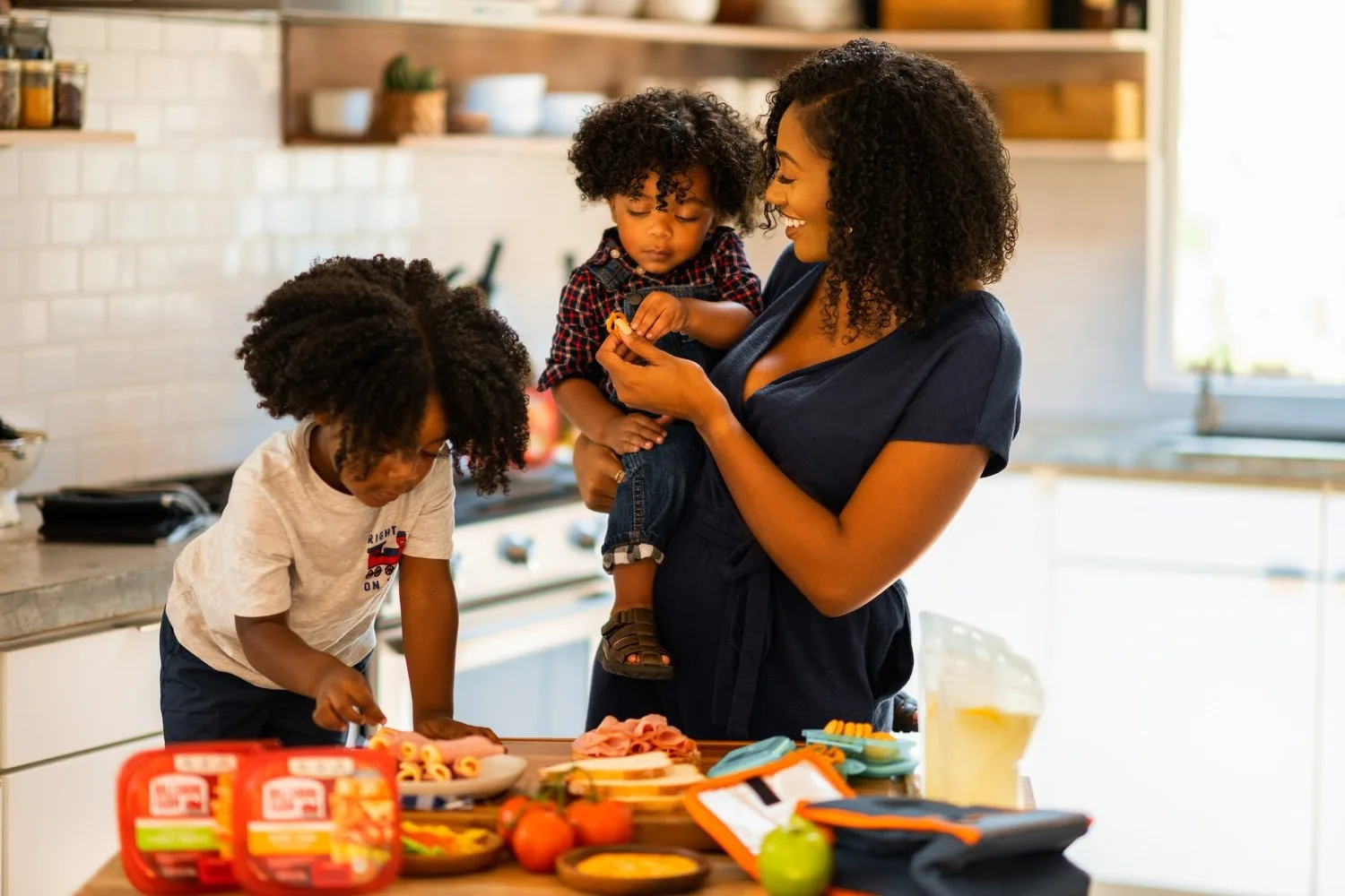 Mother cooking with her two young children in a kitchen