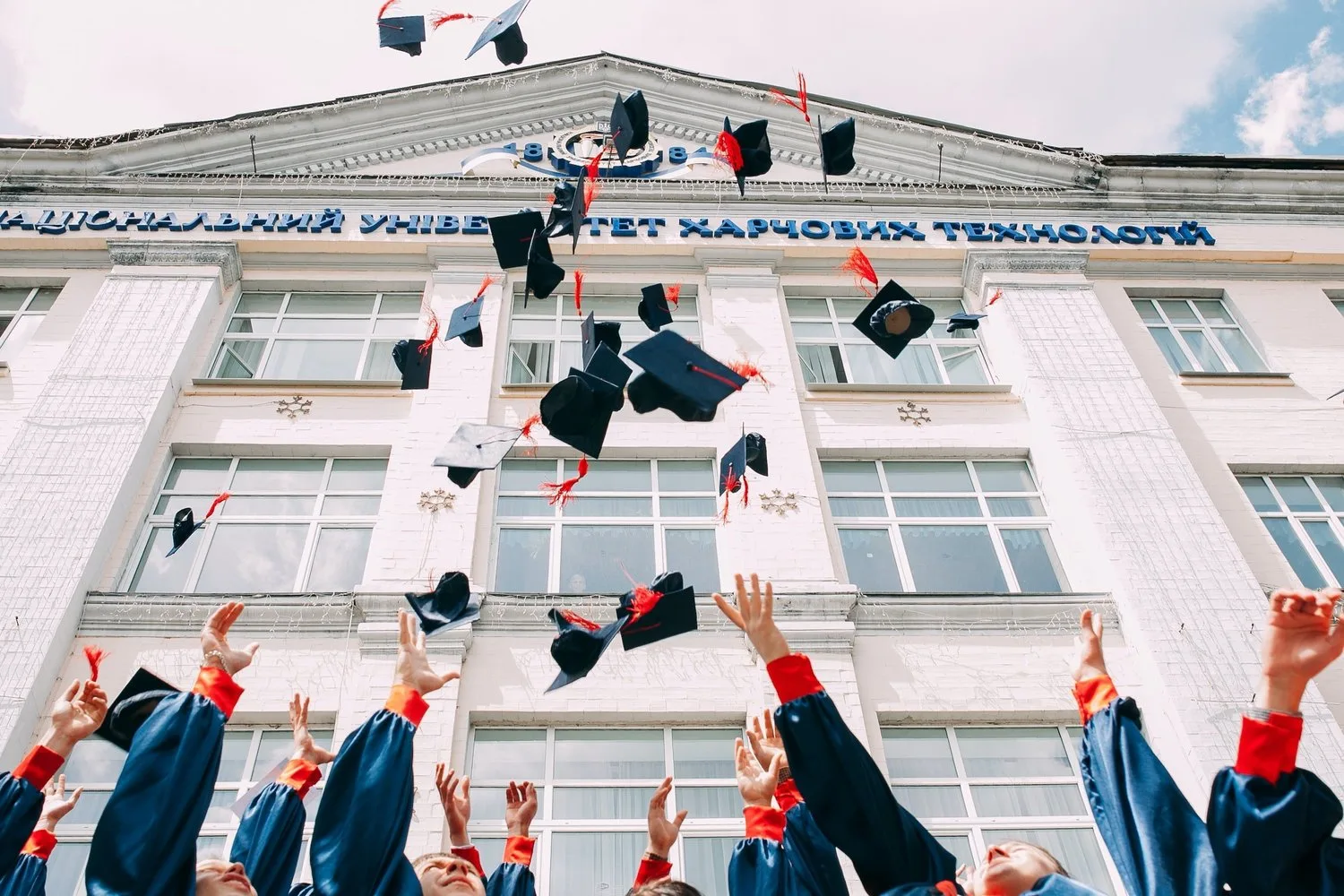 Graduates tossing their caps into the air in front of a university building