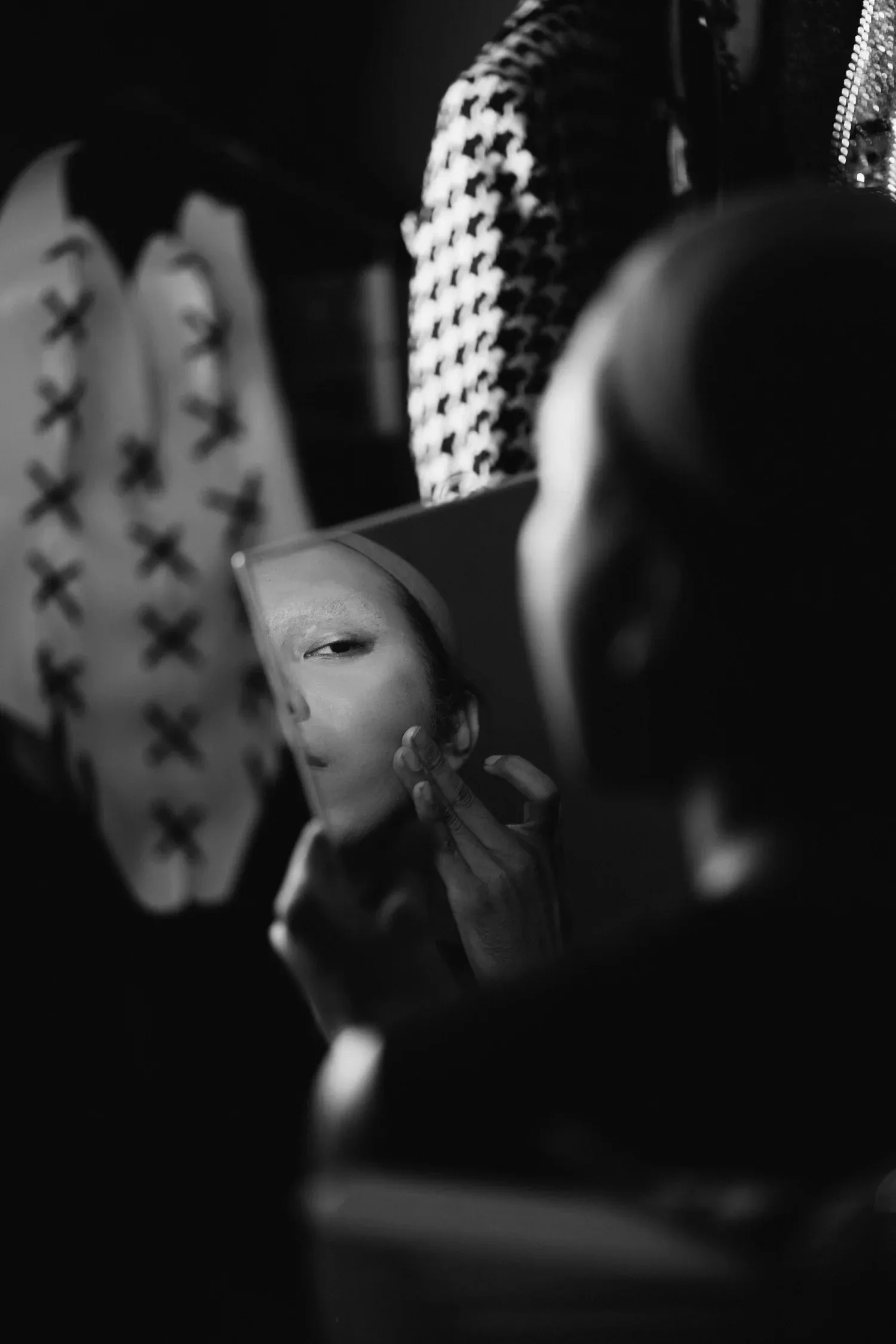 Black-and-white photo of a person partly hidden behind a mask in a crowd