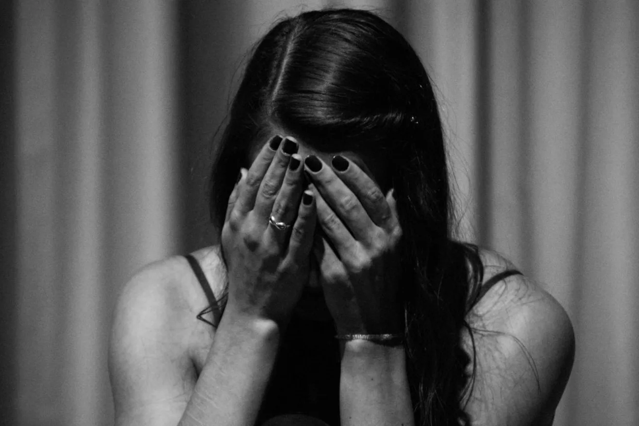 Black-and-white photo of a woman covering her face with both hands