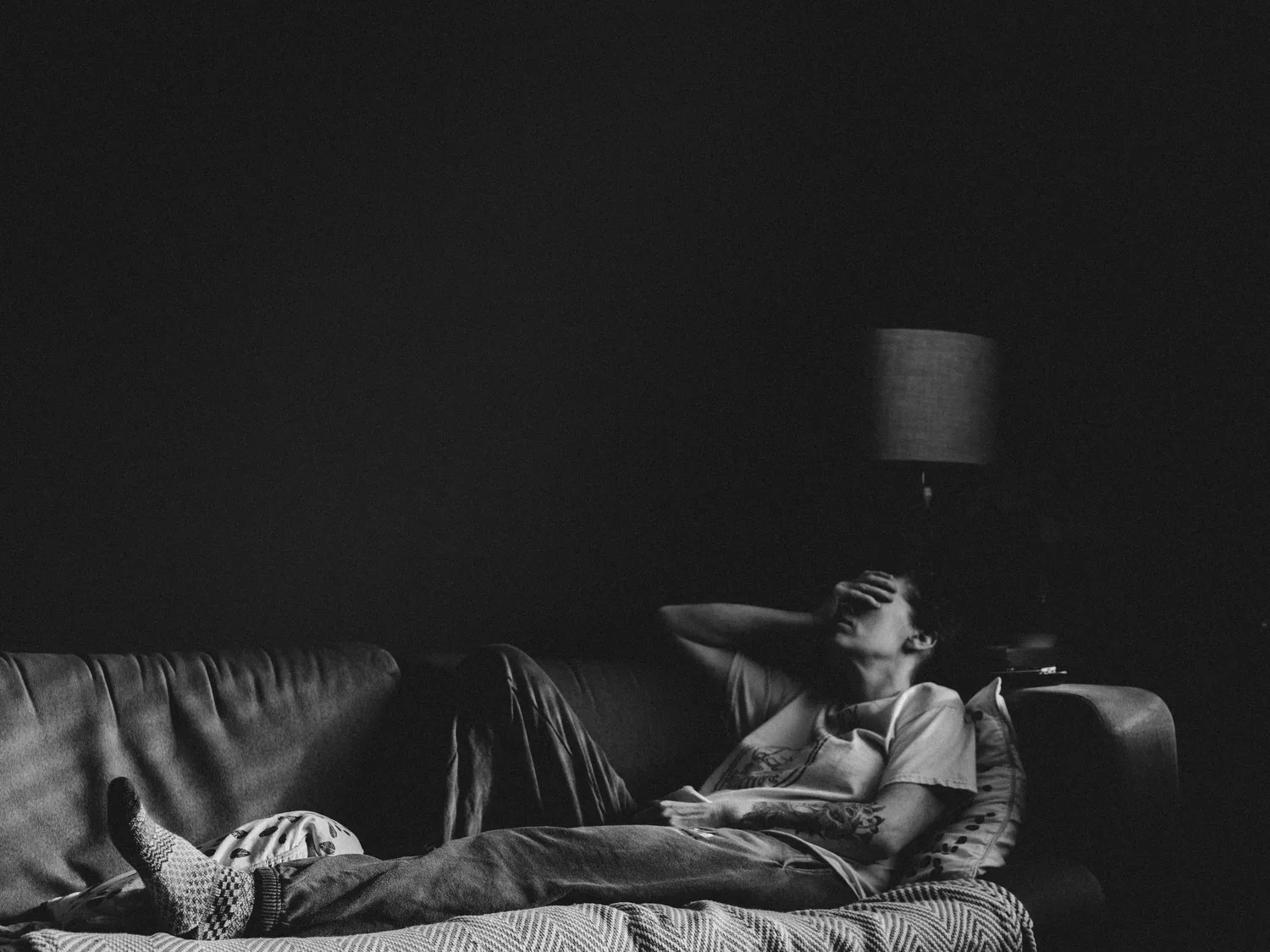 Person lying on a sofa in a dark room