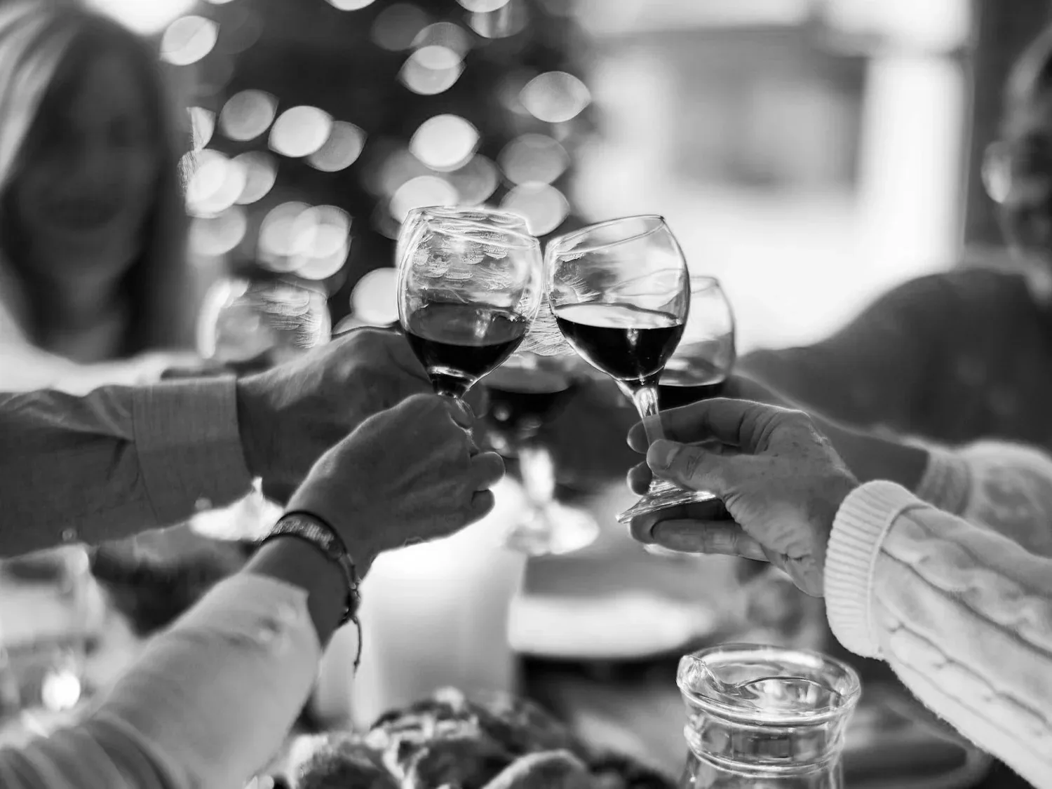 Black-and-white photo of friends clinking wine glasses at a table