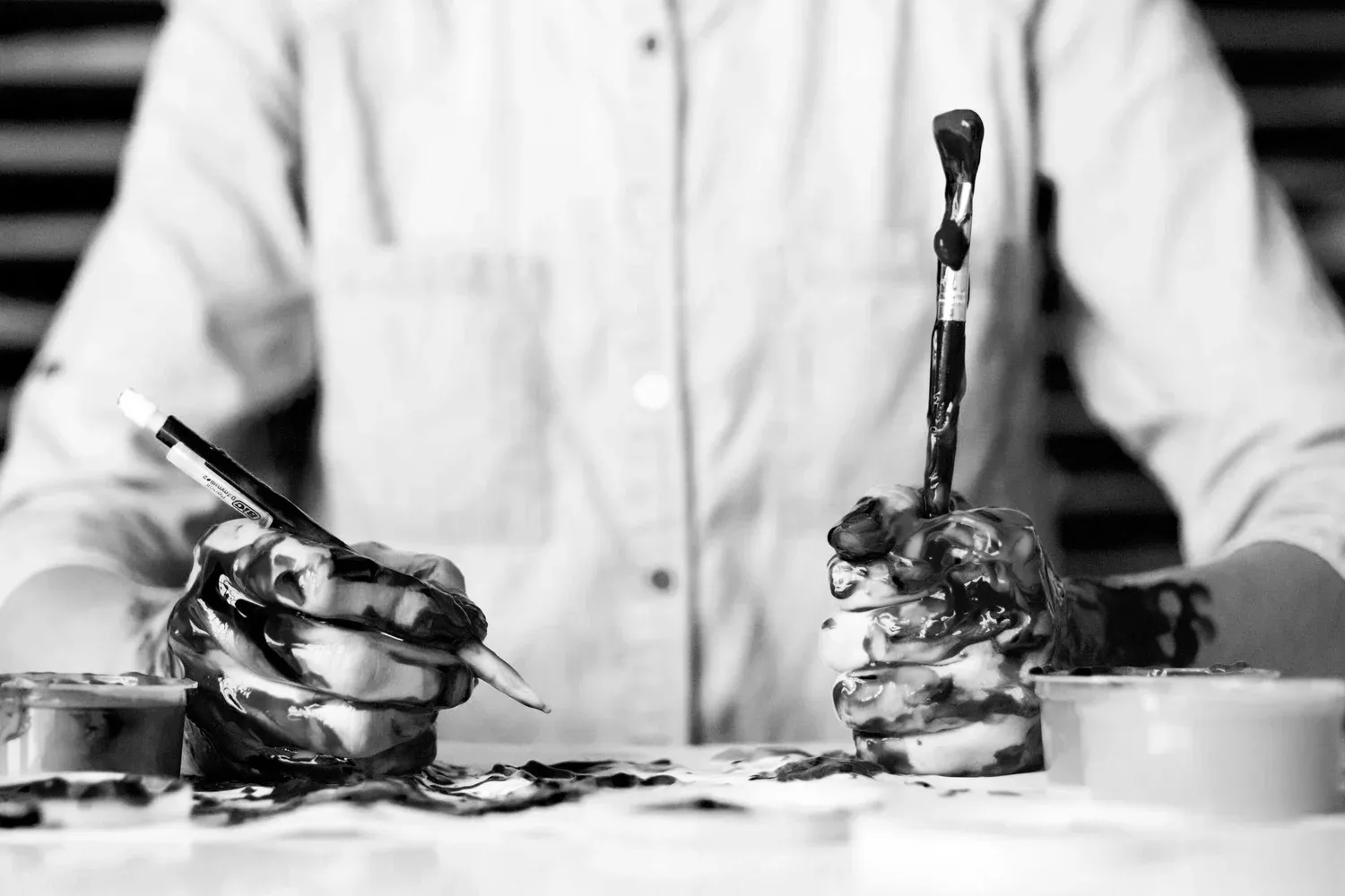 Black-and-white photo of a person in a white coat working at a cluttered counter
