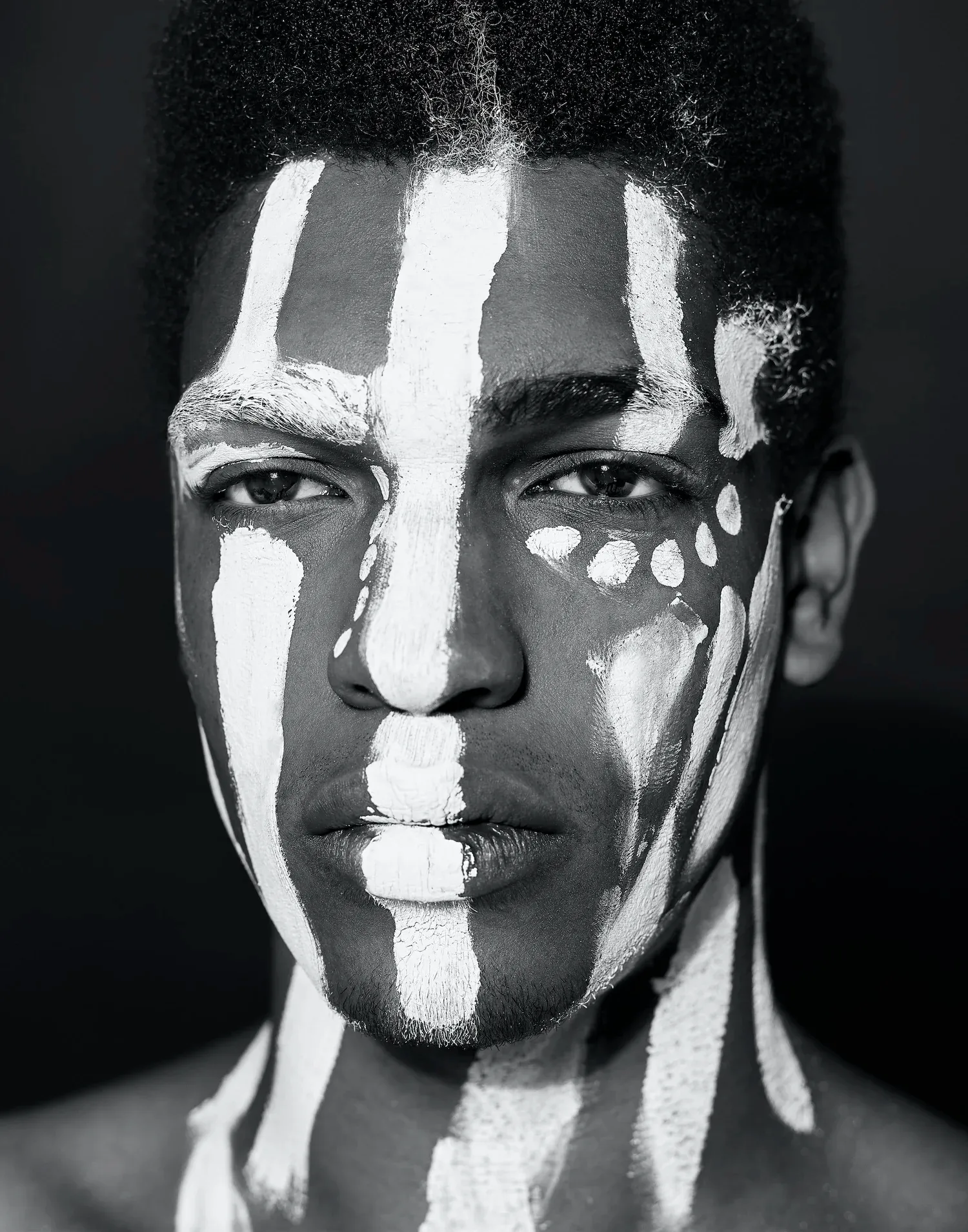 Black-and-white portrait of a man with white paint lines across his face