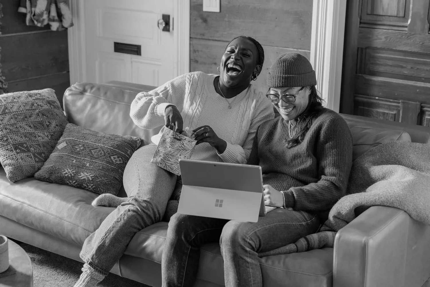 Black-and-white photo of two friends laughing on a sofa