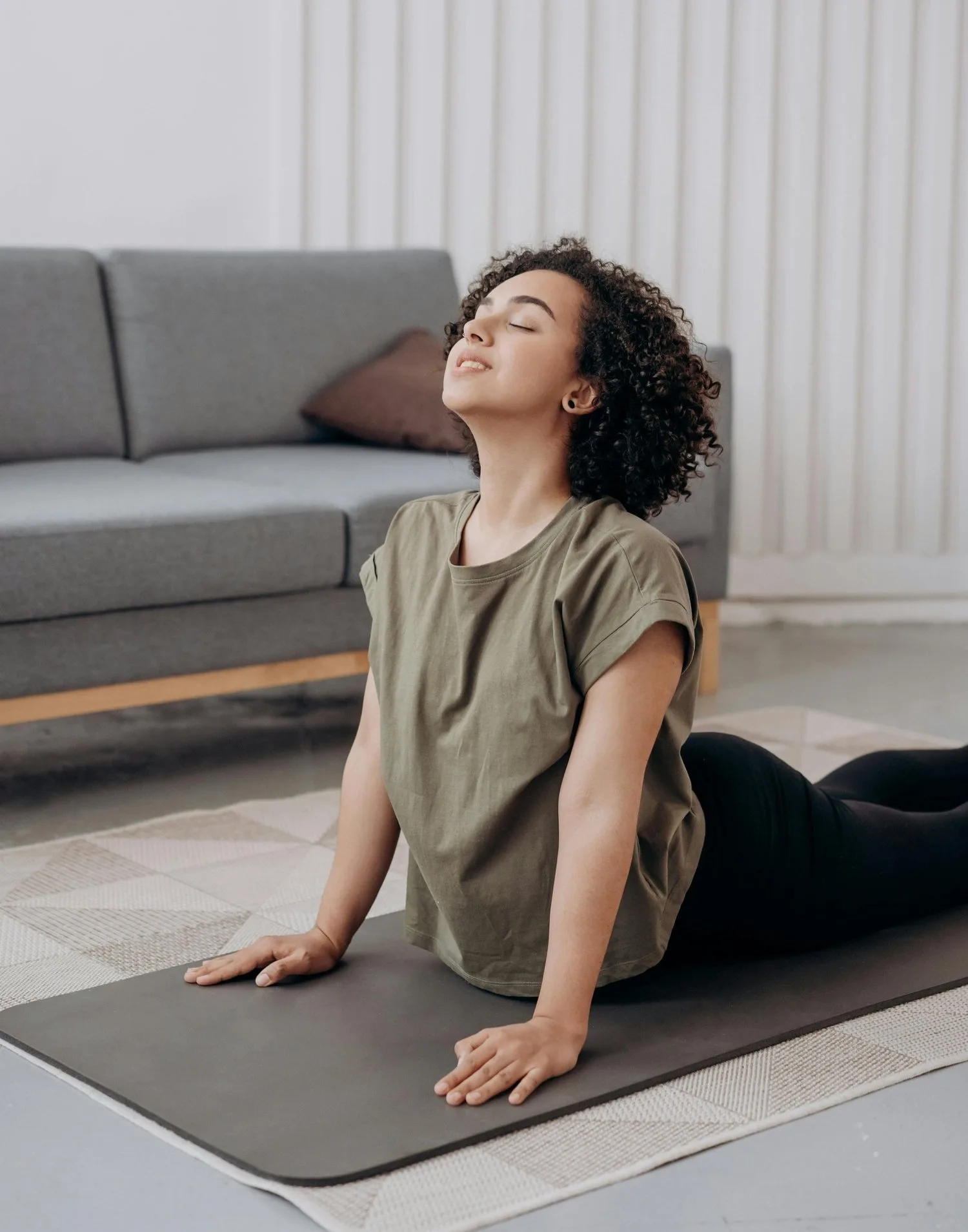 Woman stretching on a yoga mat at home with her face tilted upward