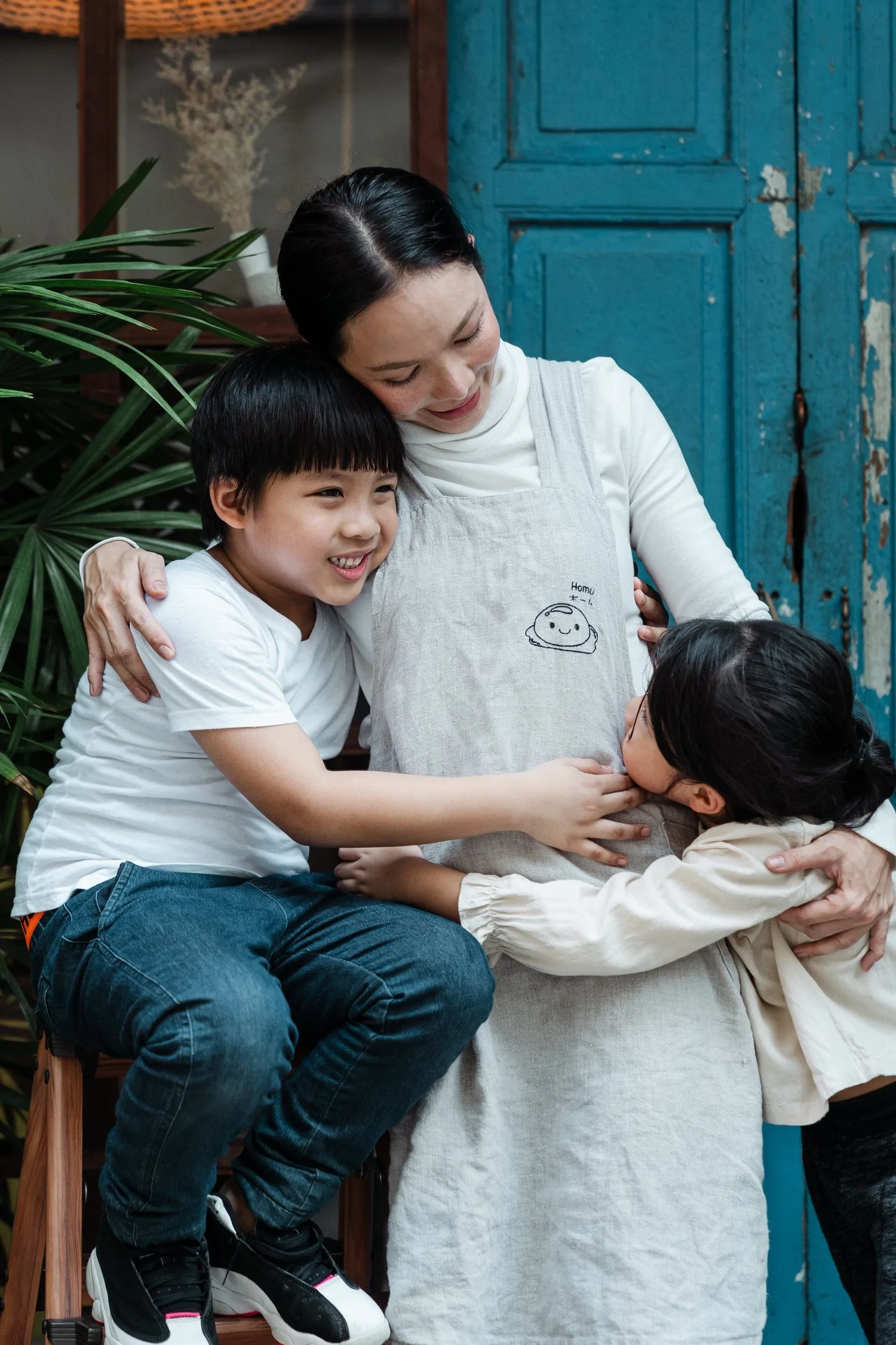 Mother hugging her two young sons in a doorway