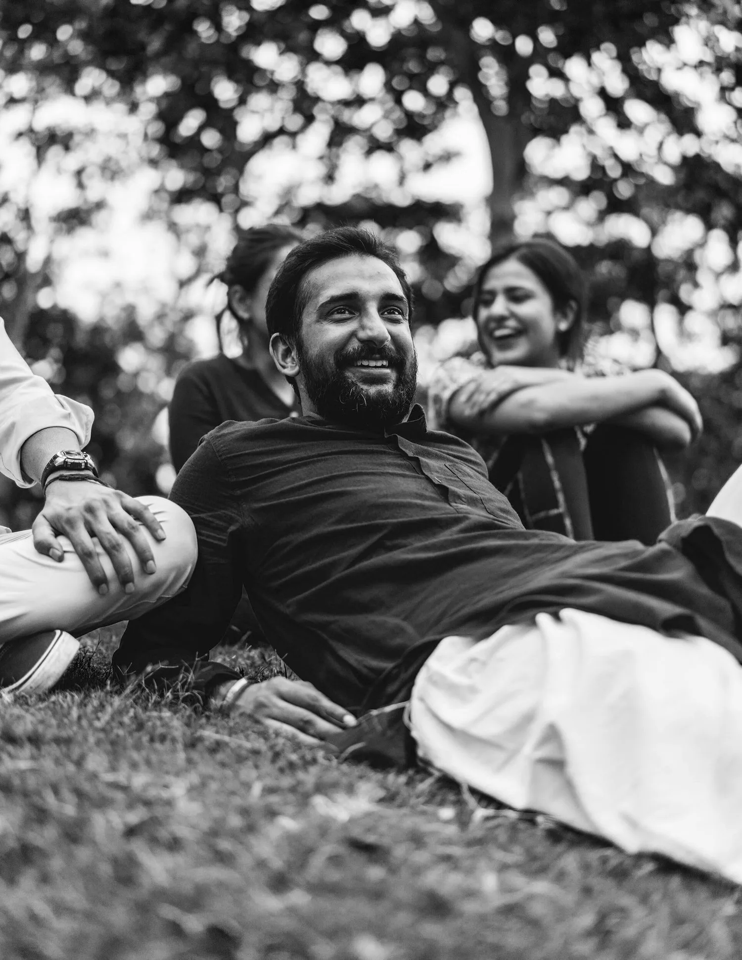 Black-and-white photo of a man relaxing on the grass, smiling