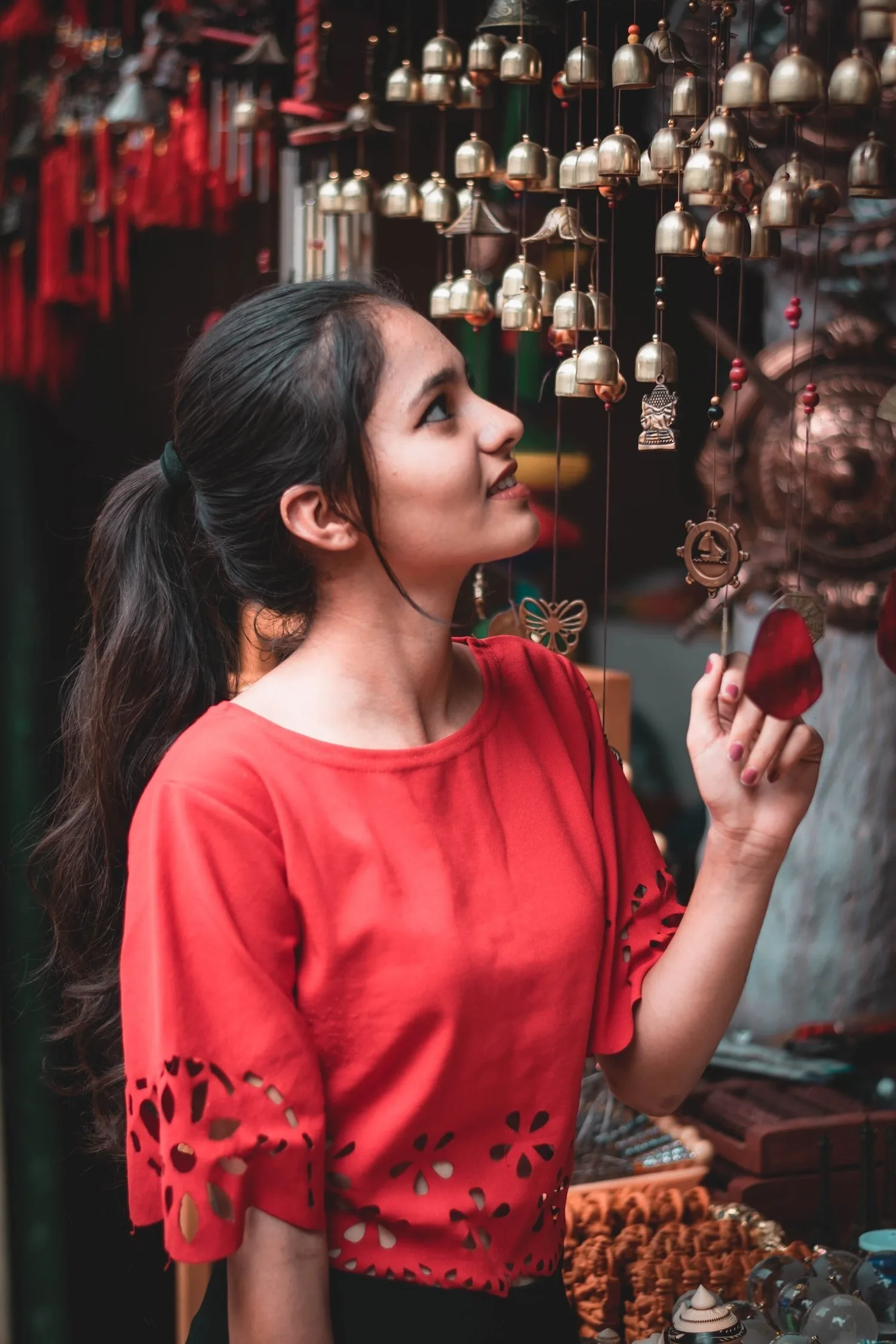 Young woman in a red top smiling in a market filled with hanging lanterns