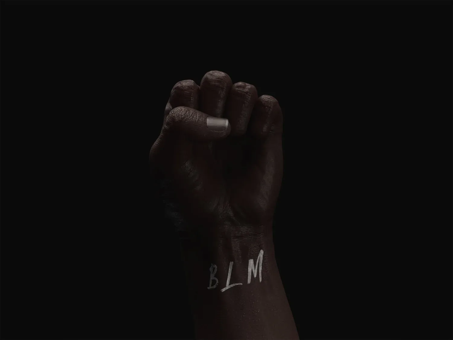 Raised fist in dim light against a black background