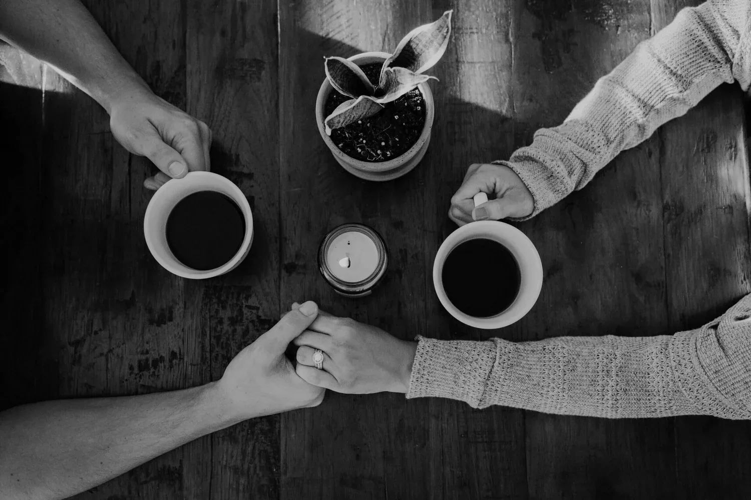 Two people sharing coffee at a wooden table, seen from above