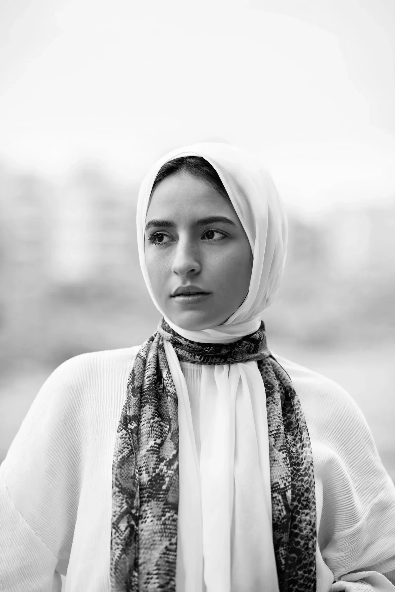 Black-and-white portrait of a young woman in a hijab looking to the side