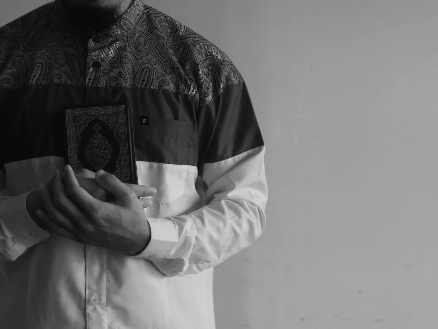 Black-and-white photo of a person holding a small book close to their chest