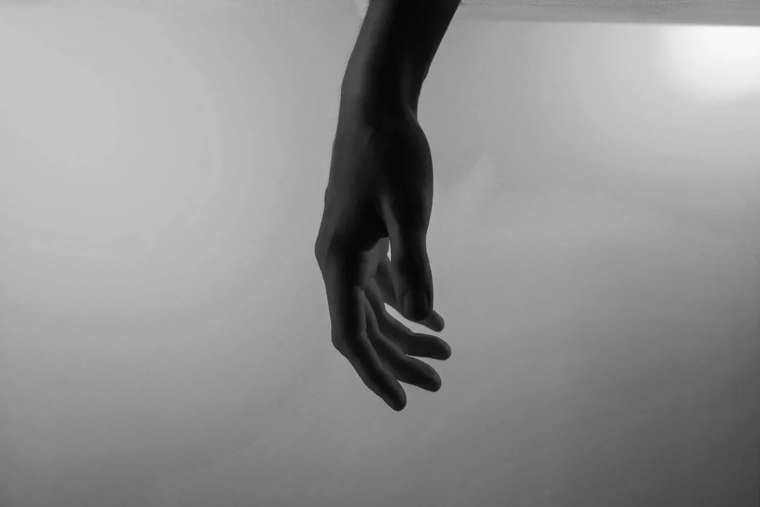 Black-and-white photo of a single hand reaching down from above