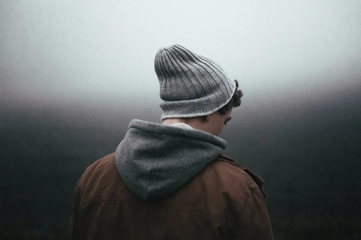 Person in a knit hat seen from behind against a foggy background