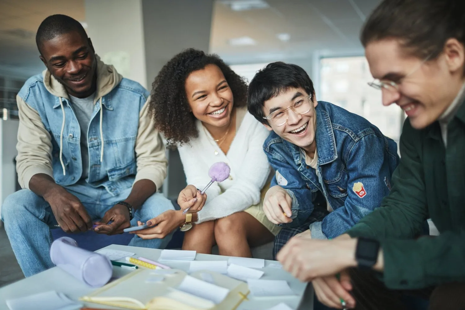 Group of friends laughing together around a table playing a game