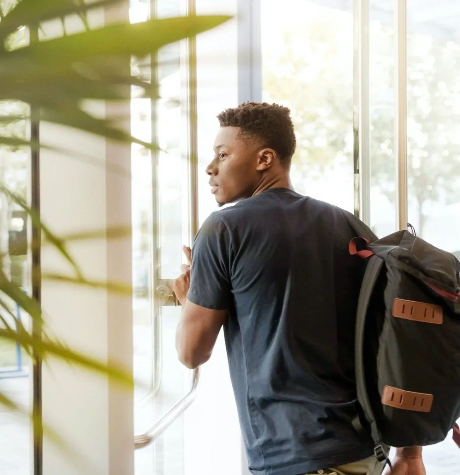 Young man with a backpack standing in a bright hallway