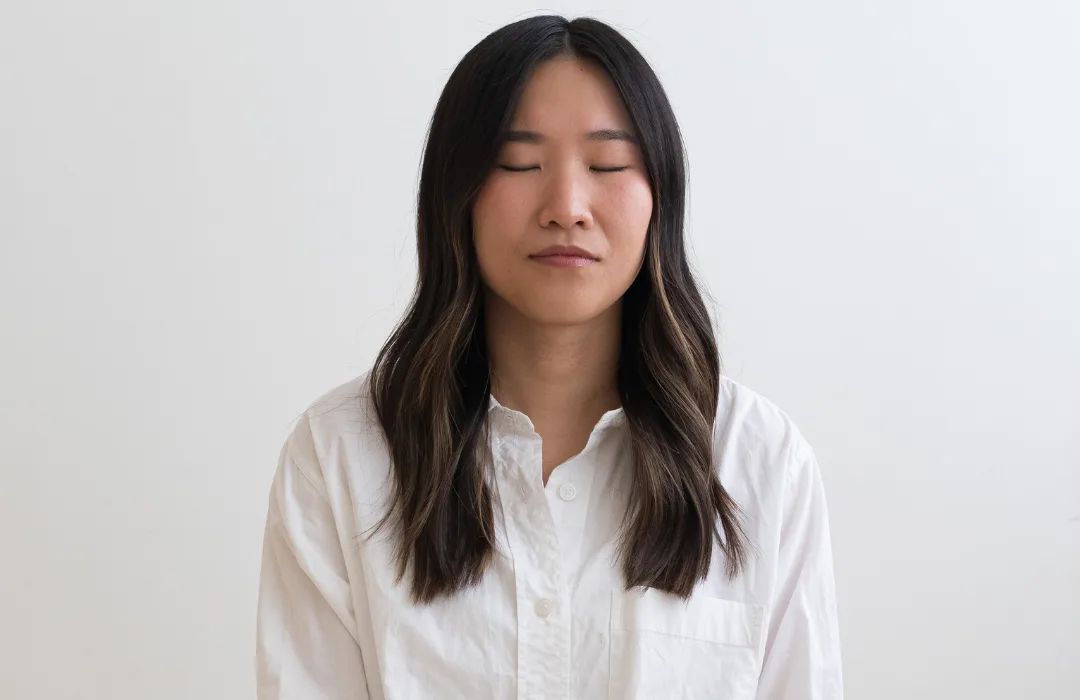 Woman in a white shirt with eyes closed and a calm expression