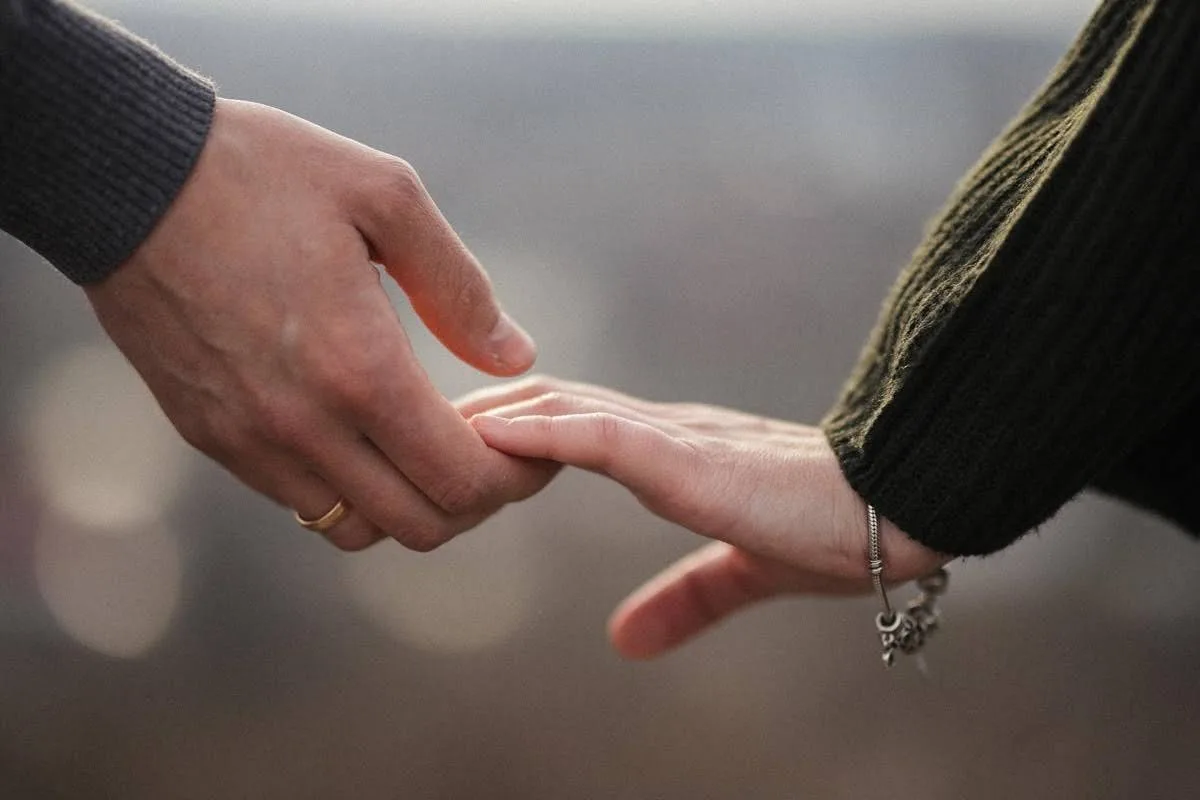 Two hands reaching toward each other, fingertips touching