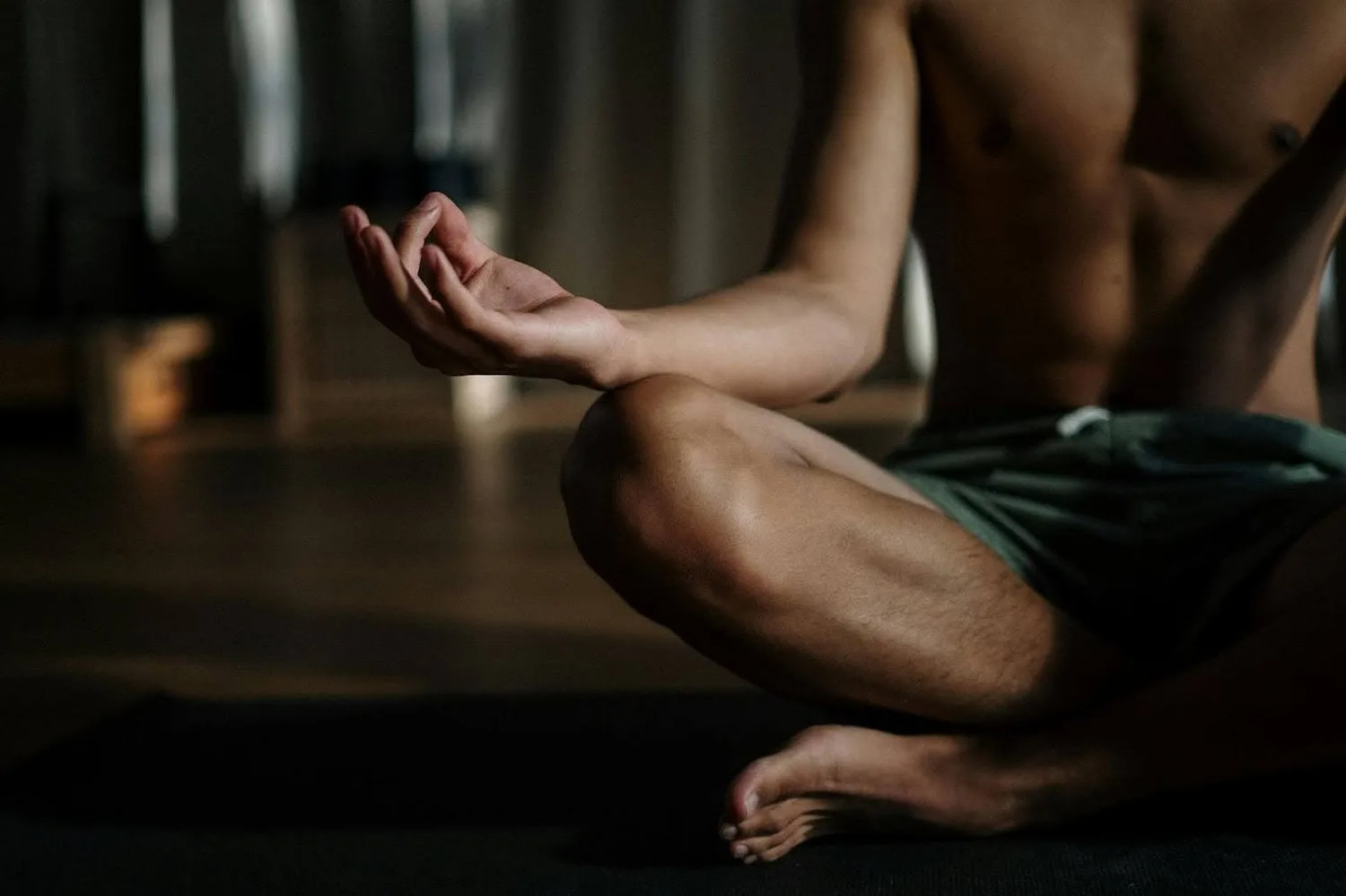 Person seated cross-legged in meditation in a dimly lit room