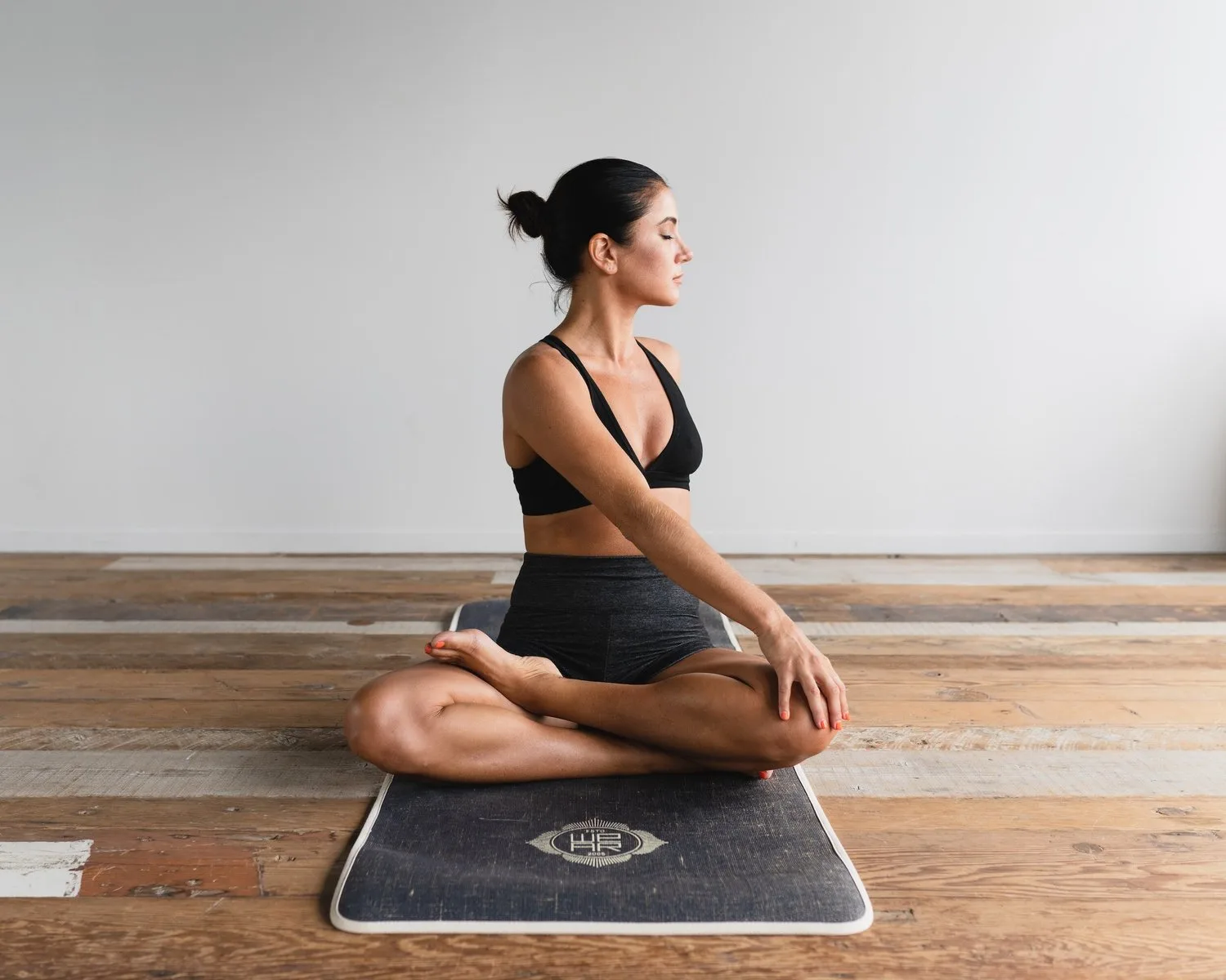 Woman sitting cross-legged on a meditation cushion in a bare room