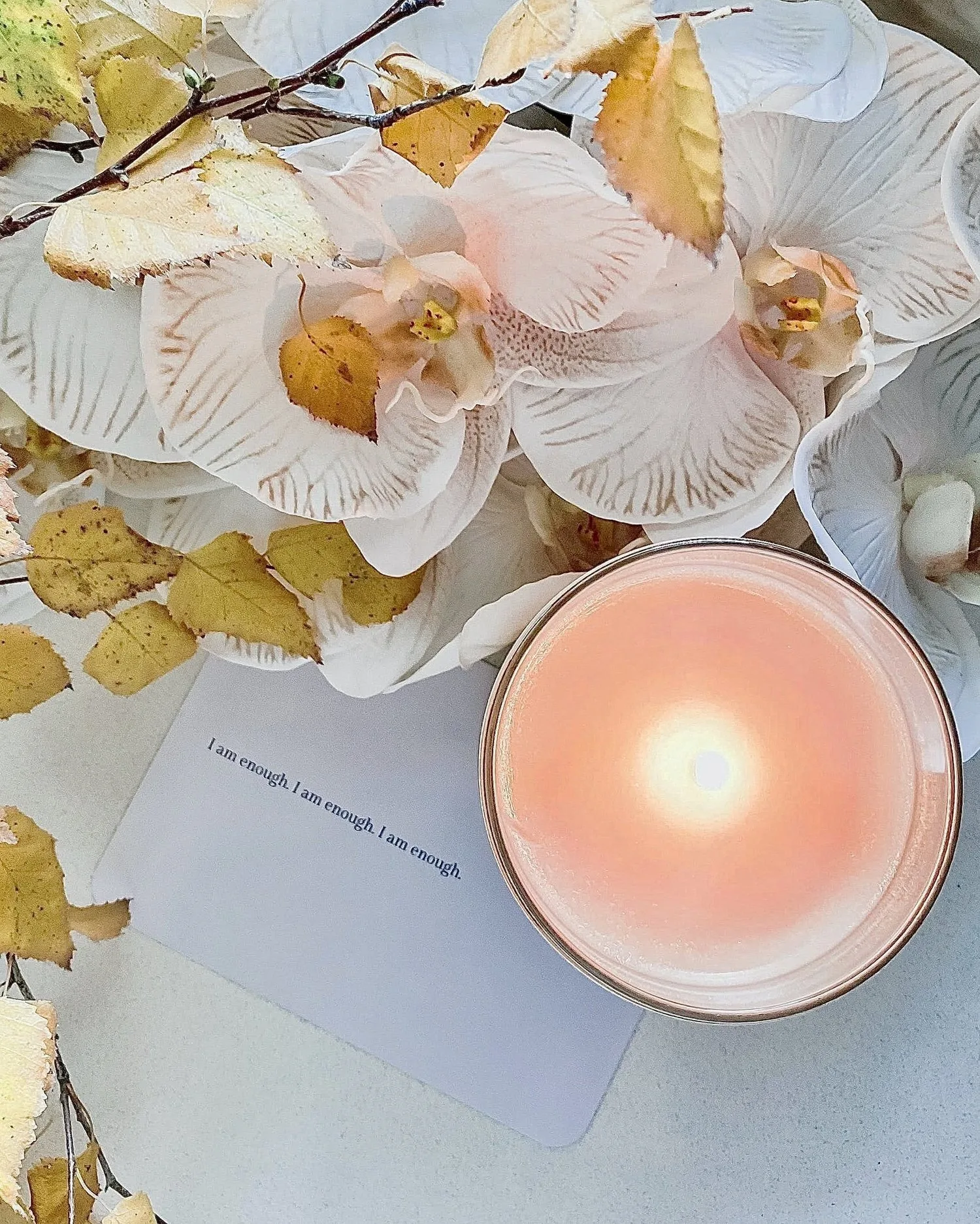 Lit candle surrounded by dried flowers and a handwritten card