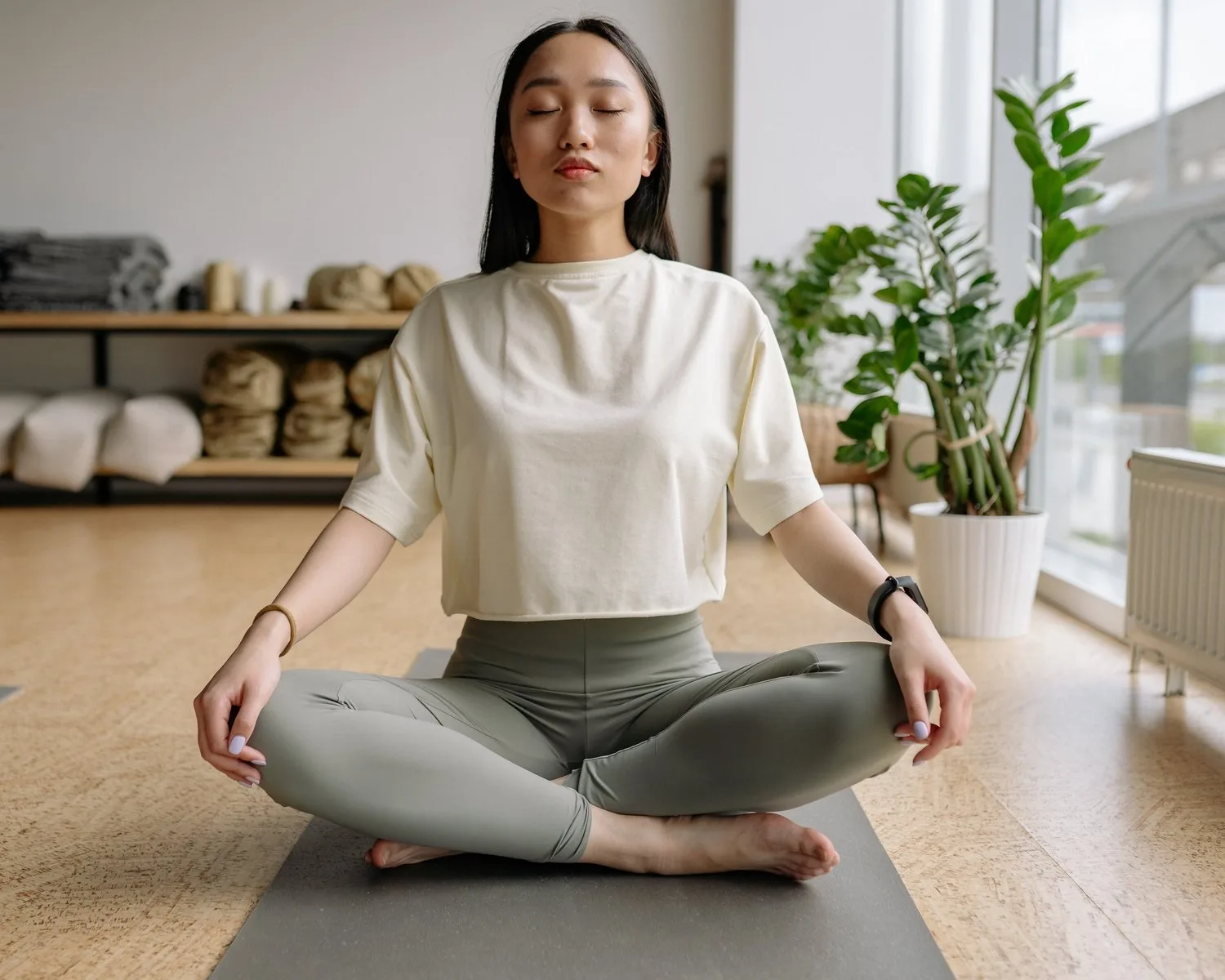 Woman meditating cross-legged on a mat in a bright studio